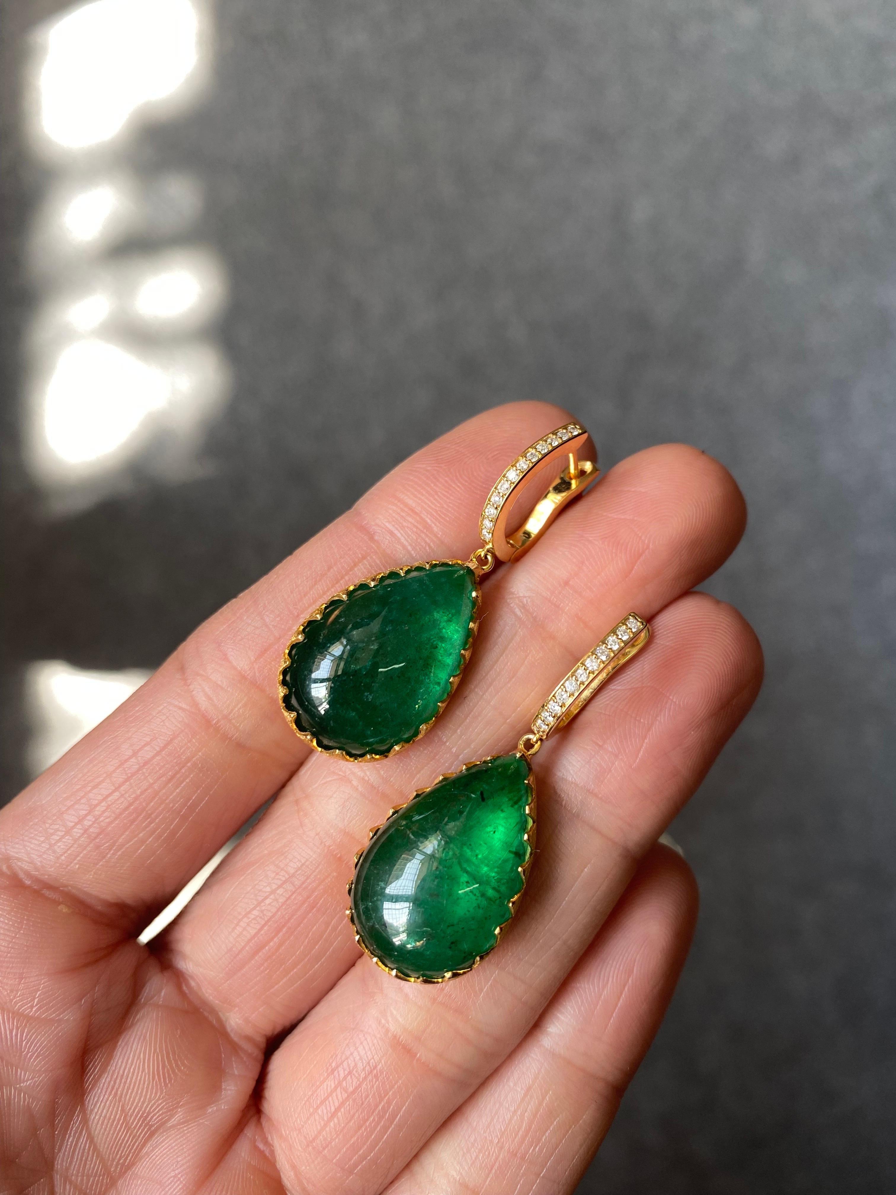 A beautiful pair of classic 28.61 carat pear shaped cabochon Zambian Emeralds set in solid matte finish 18K Yellow Gold, with VS quality White Diamonds. The Emeralds are completely transparent, with an eye-catching vivid green color and great
