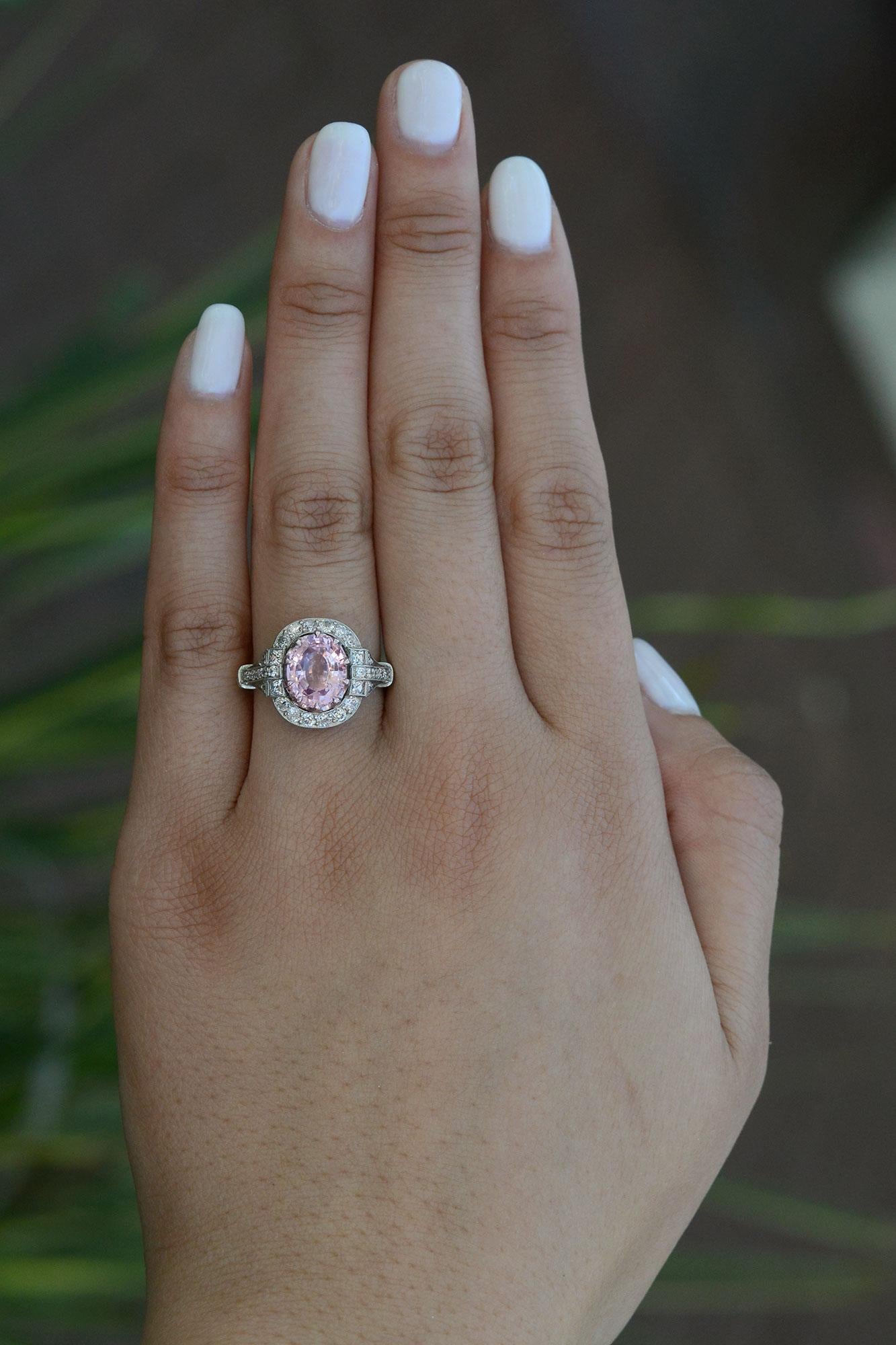 Un saphir Padparadscha brillant et blush est le point fort de cette magnifique bague de fiançailles détaillée.  D'une couleur rose orangée lustrée et précieuse, ce saphir de Ceylan, le plus prisé, tire son nom du cingalais, qui signifie 