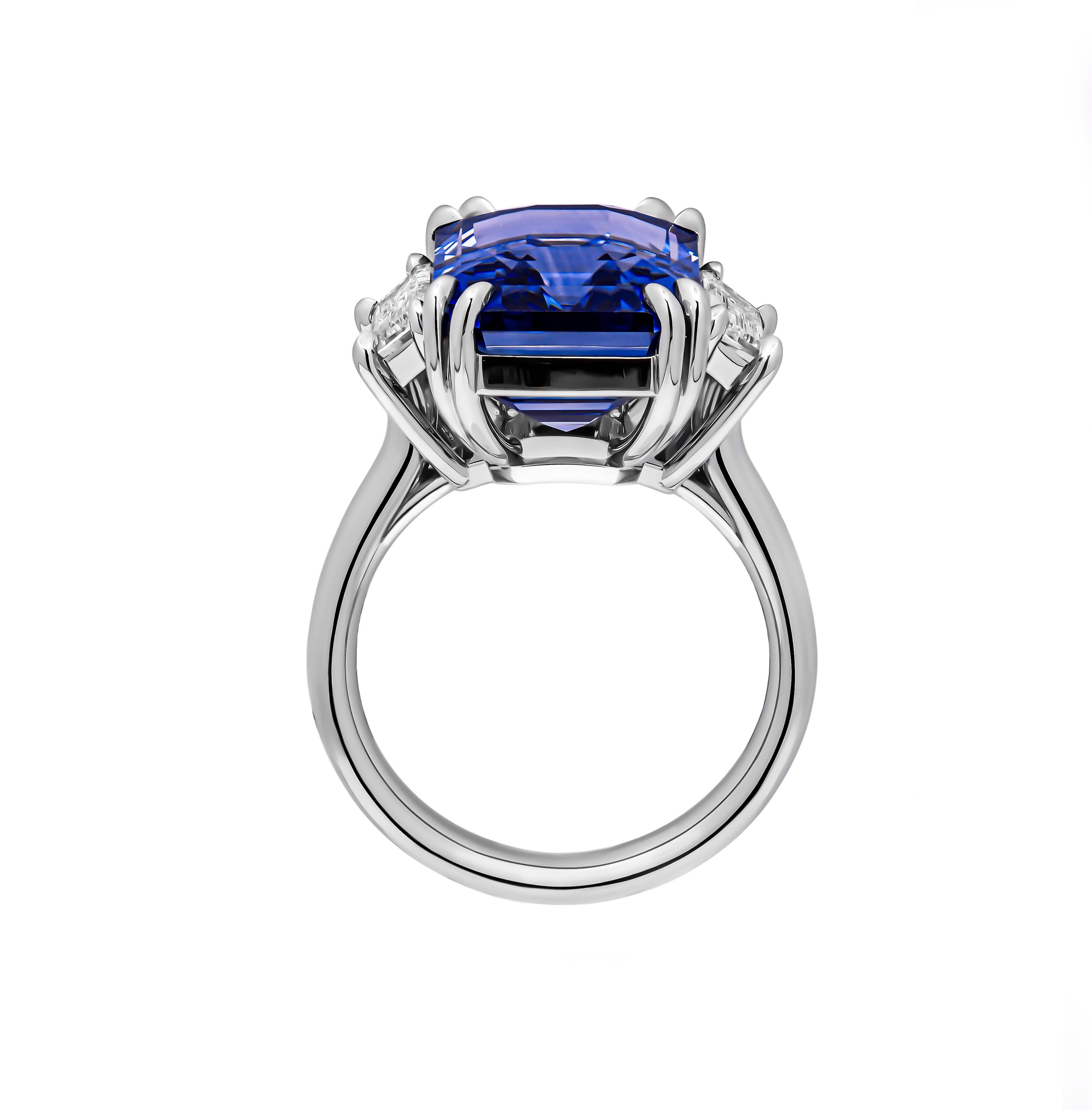 Behold a masterpiece of unparalleled beauty and sophistication: a magnificent three-stone ring, exquisitely crafted in lustrous 950 platinum. At its heart lies a captivating 12.02 carat emerald-cut blue sapphire, reminiscent of the deep azure hues