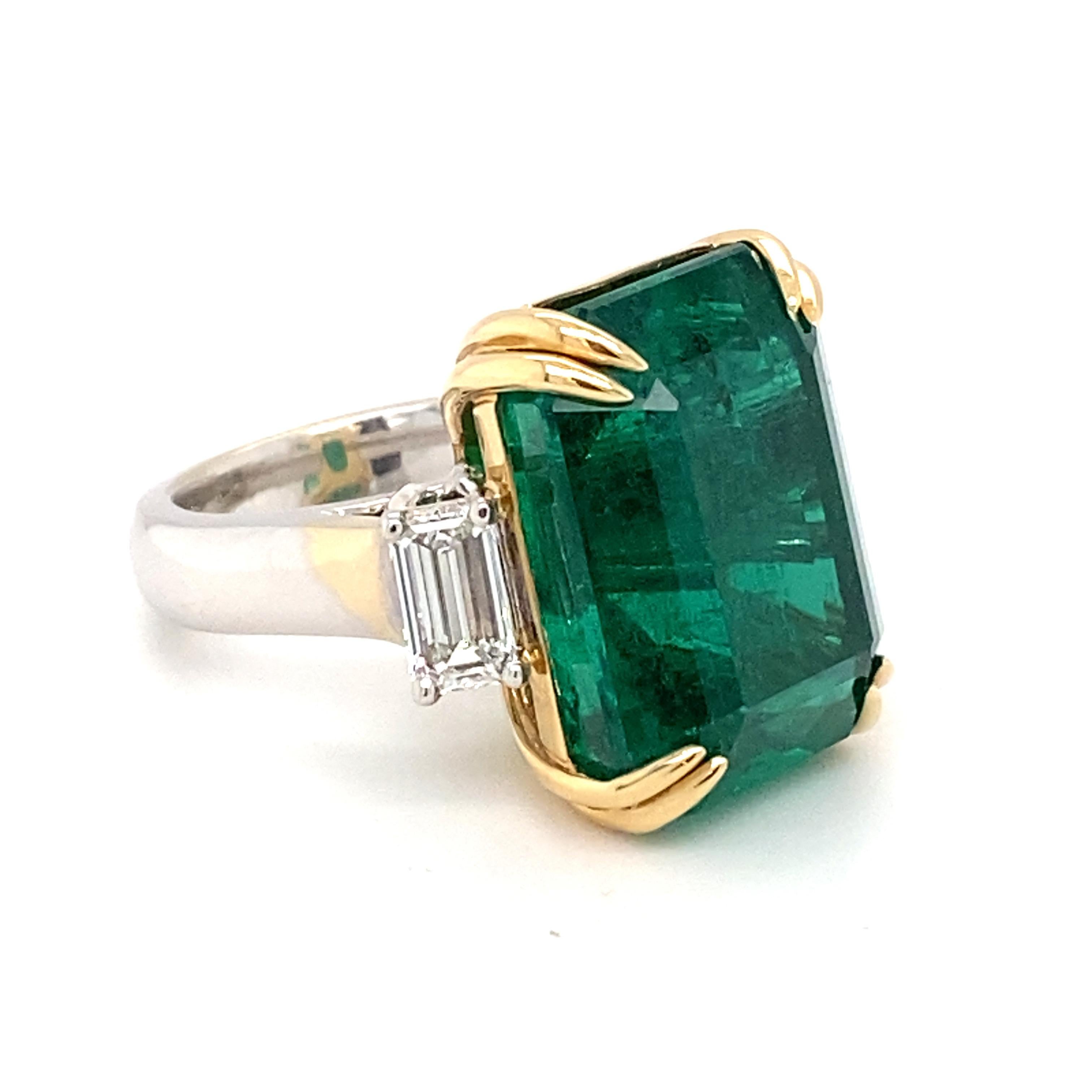 Cette bague opulente est ornée d'une émeraude certifiée de 30,27 carats de taille octogonale très recherchée et de deux diamants blancs de 1,41 carat de taille émeraude à l'est et à l'ouest. Monté en double sertissage en or 18 carats de deux tons.