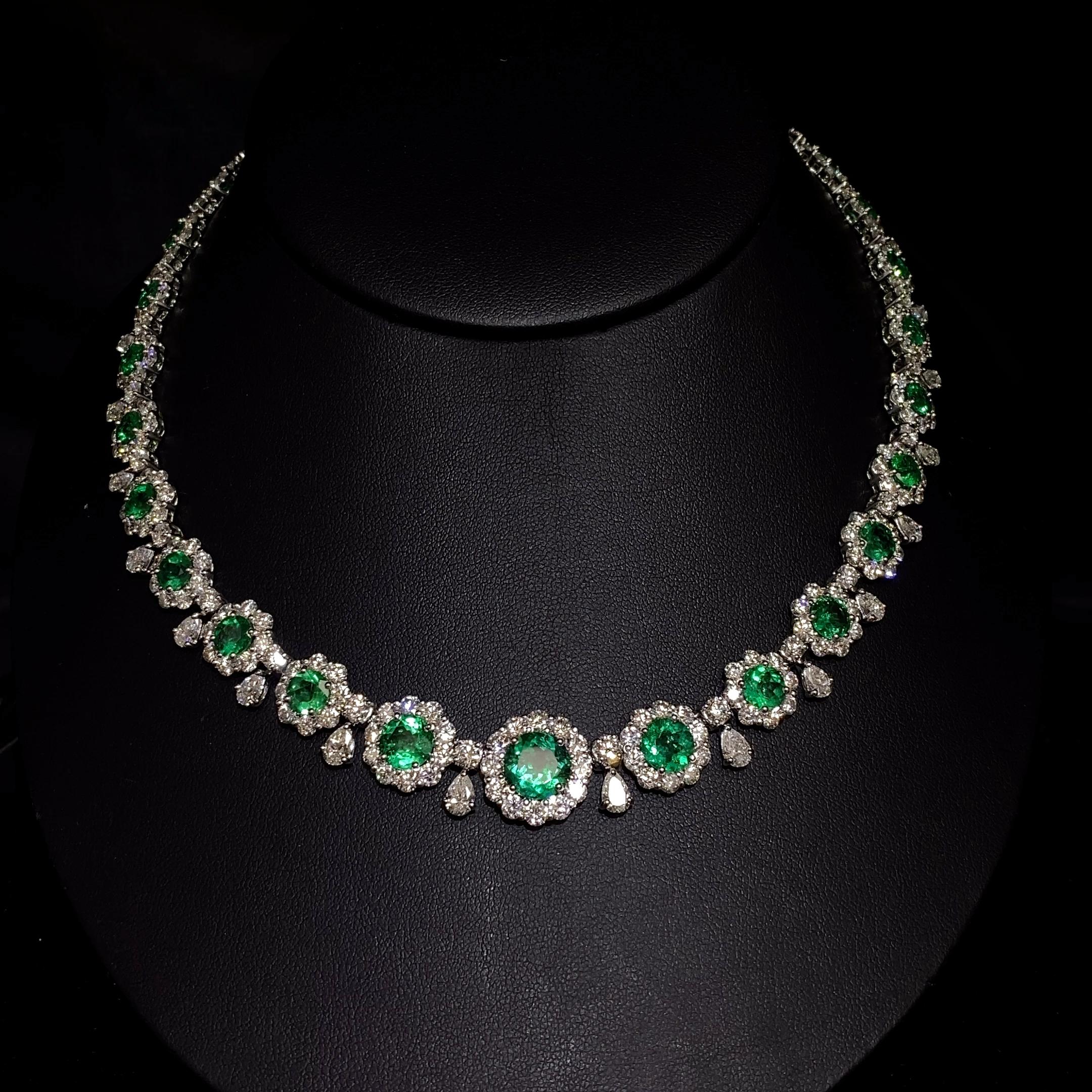 This stunning necklace features a captivating design that showcases vibrant round green emeralds, known for their rich green hue. The piece is intricately crafted and accentuated by a combination of brilliant mixed-cut diamonds, including round and