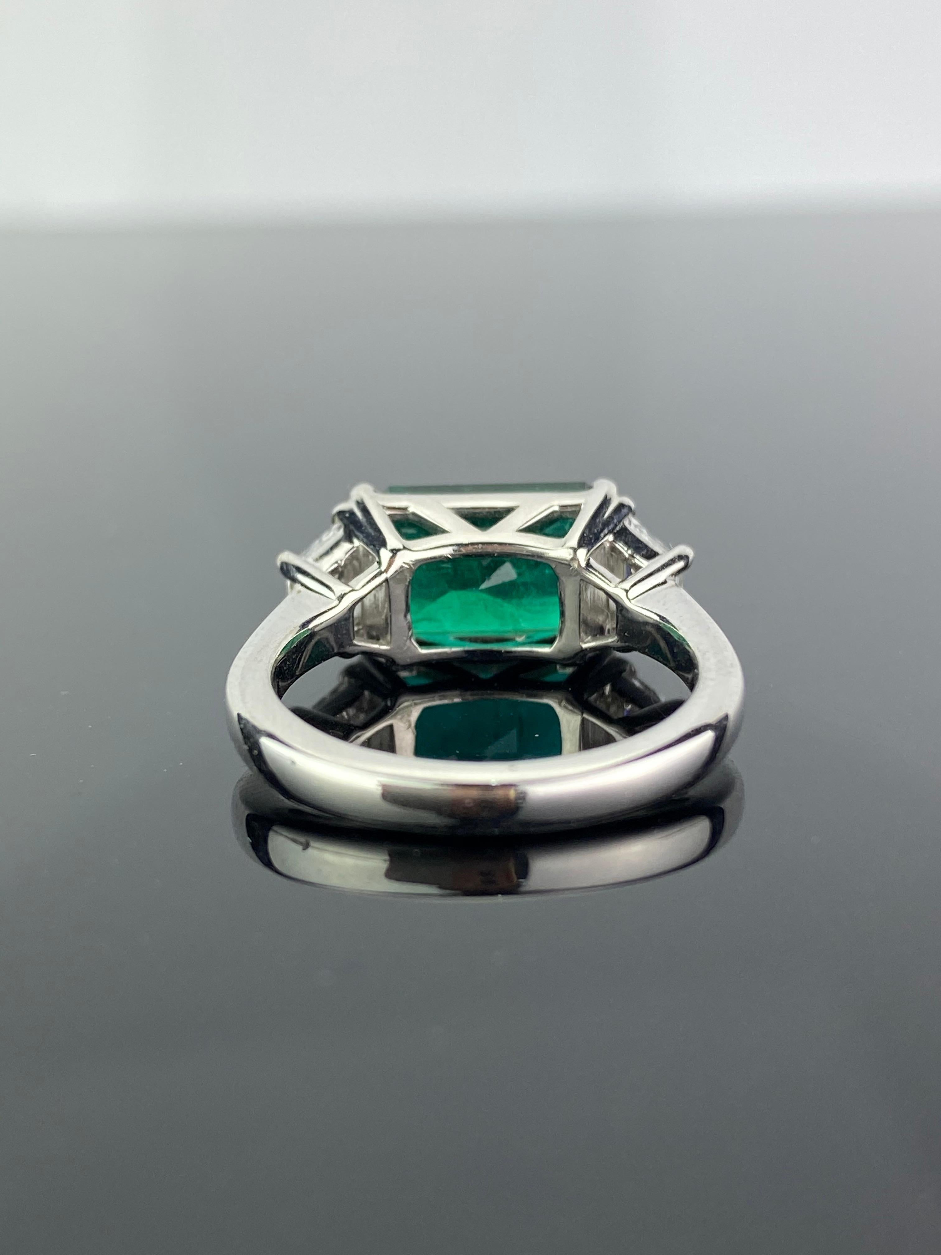 A stunning 3.42 carat emerald cut Zambian Emerald and 0.44 carat VS quality, G color White Diamond three-stone engagement ring. The Emerald is transparent, with very few naturally occurring inclusions. The cut of the stone is excellent, there is