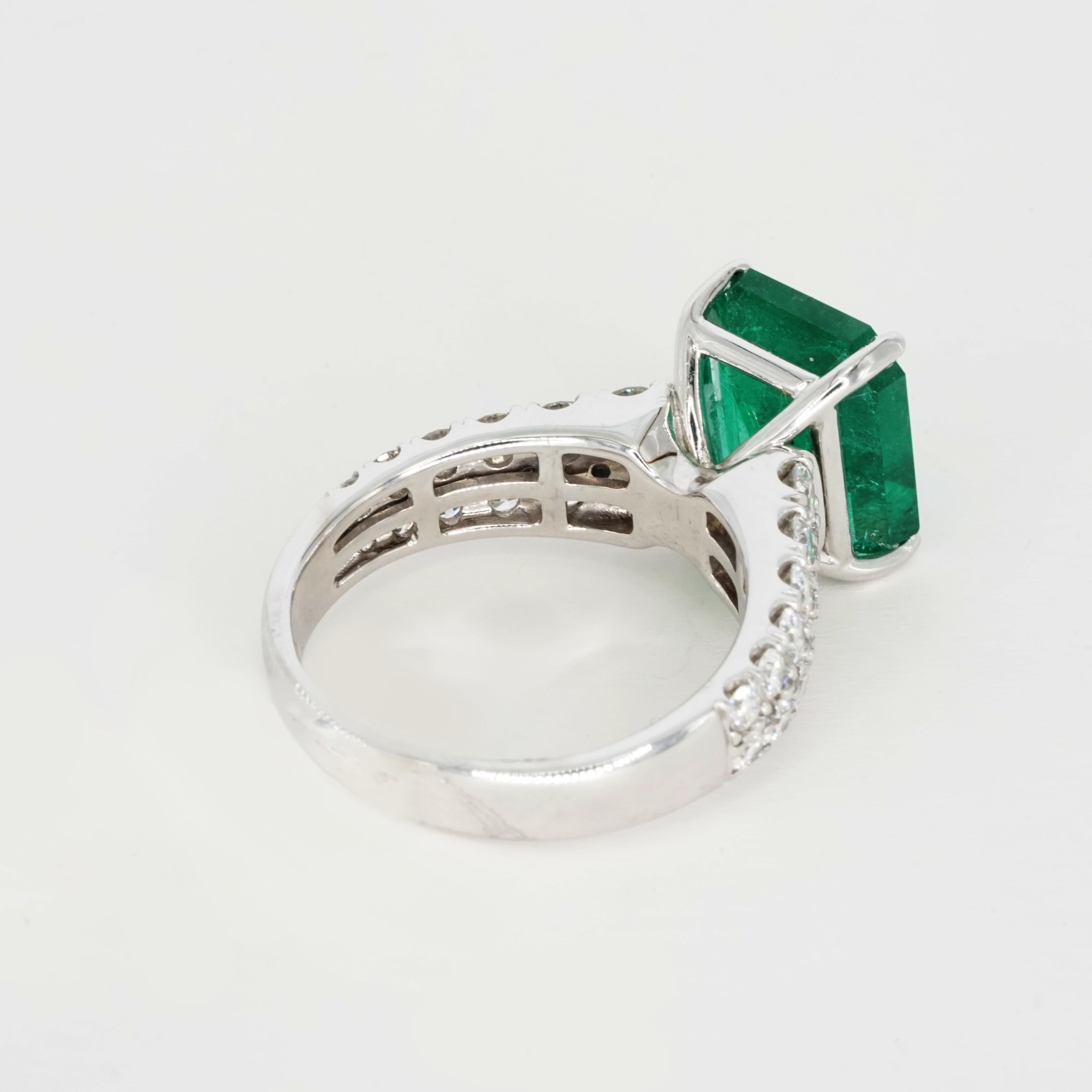 This stunning ring features a natural emerald with a deep, vibrant green hue, expertly cut in an octagonal step cut, which enhances its clarity and brilliance. Originating from the renowned mines of Zambia, the emerald captures the light