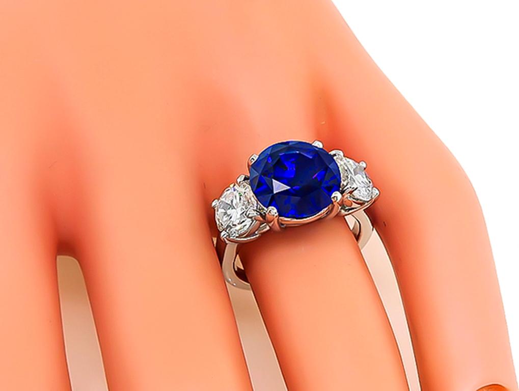 Este impresionante anillo de aniversario de platino está centrado con un precioso zafiro azul real de Ceilán certificado C.Dunaigre que pesa 5,03 ct. La piedra central está acentuada por dos brillantes diamantes de talla redonda certificados por el