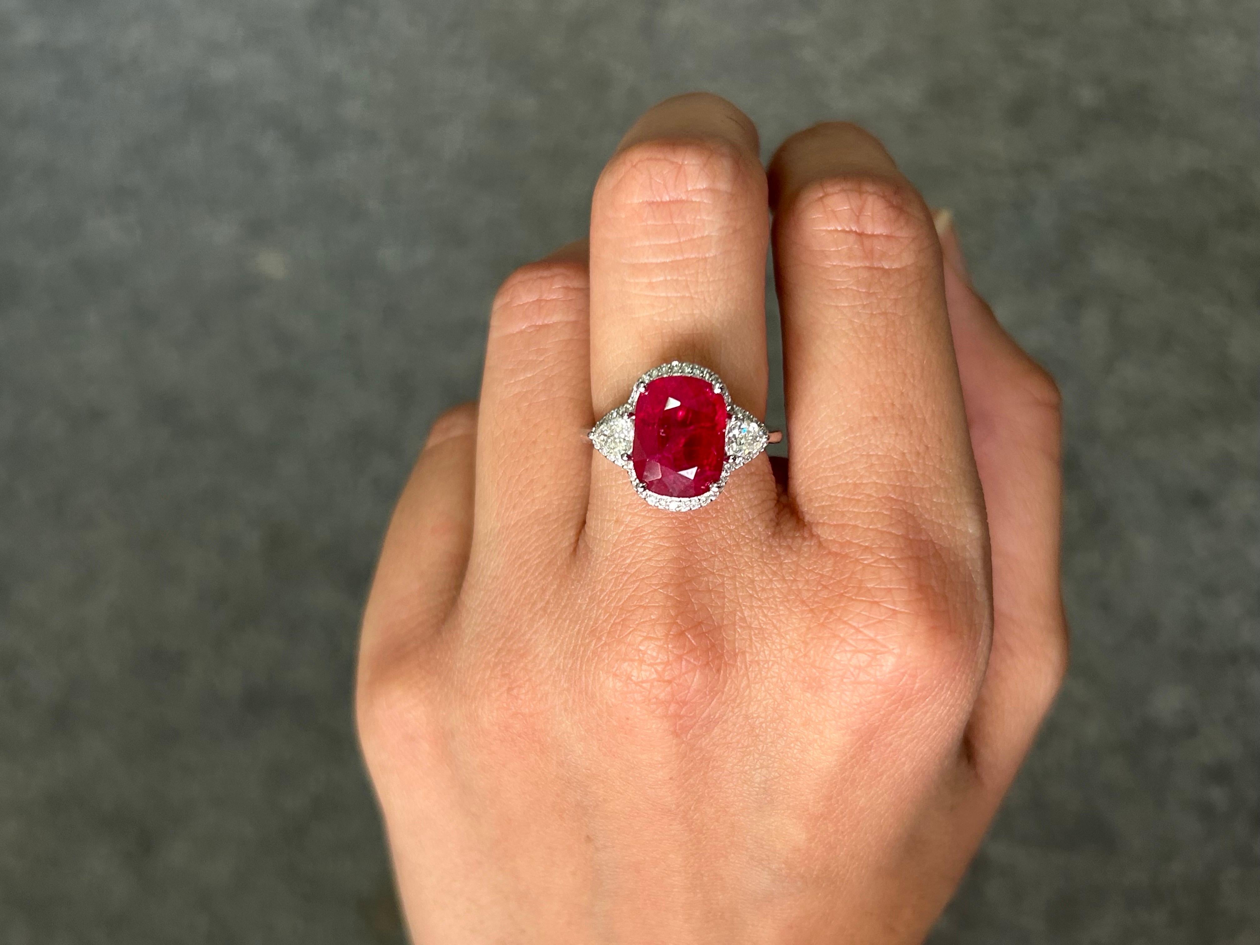 A stunning, one of a kind 5.09 carat oval shaped heated Burmese Ruby center stone with 0.44 carat VS quality side stones White Diamonds and 0.22 carat diamonds halo around it. The Ruby is of an ideal vivid red color, with a great luster and shine to
