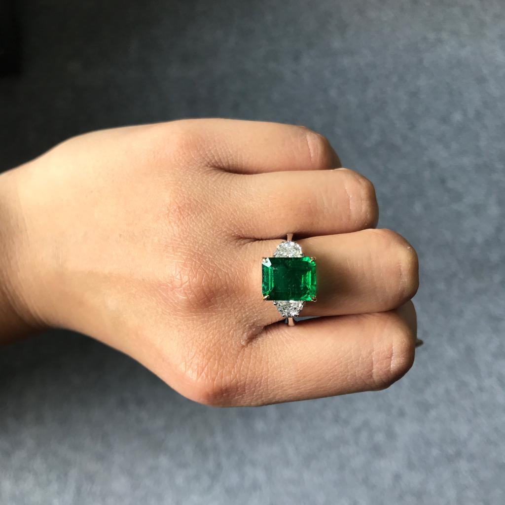 A classic three stone ring, with a 5.28 carat high quality and great colour emerald cut Zambian Emerald centre stone and 2 half-moon 0.76 carat side stone Diamonds. Currently a ring size US 6, but we can resize the ring for you without additional