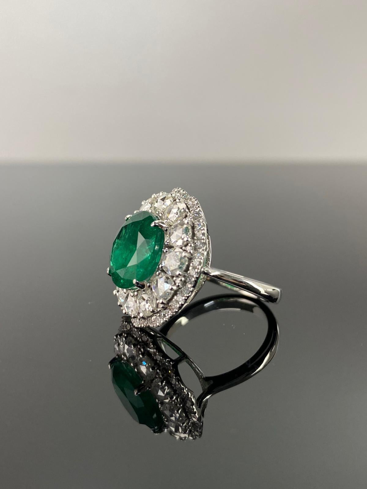 A stunning cocktail ring, with a 5.35 carat round shaped Zambian Emerald in the center surrounded with 1.64 carat rose cut White Diamonds and 0.54 carat round brilliant cut White Diamonds, all set in solid 18K White Gold. The center stone is