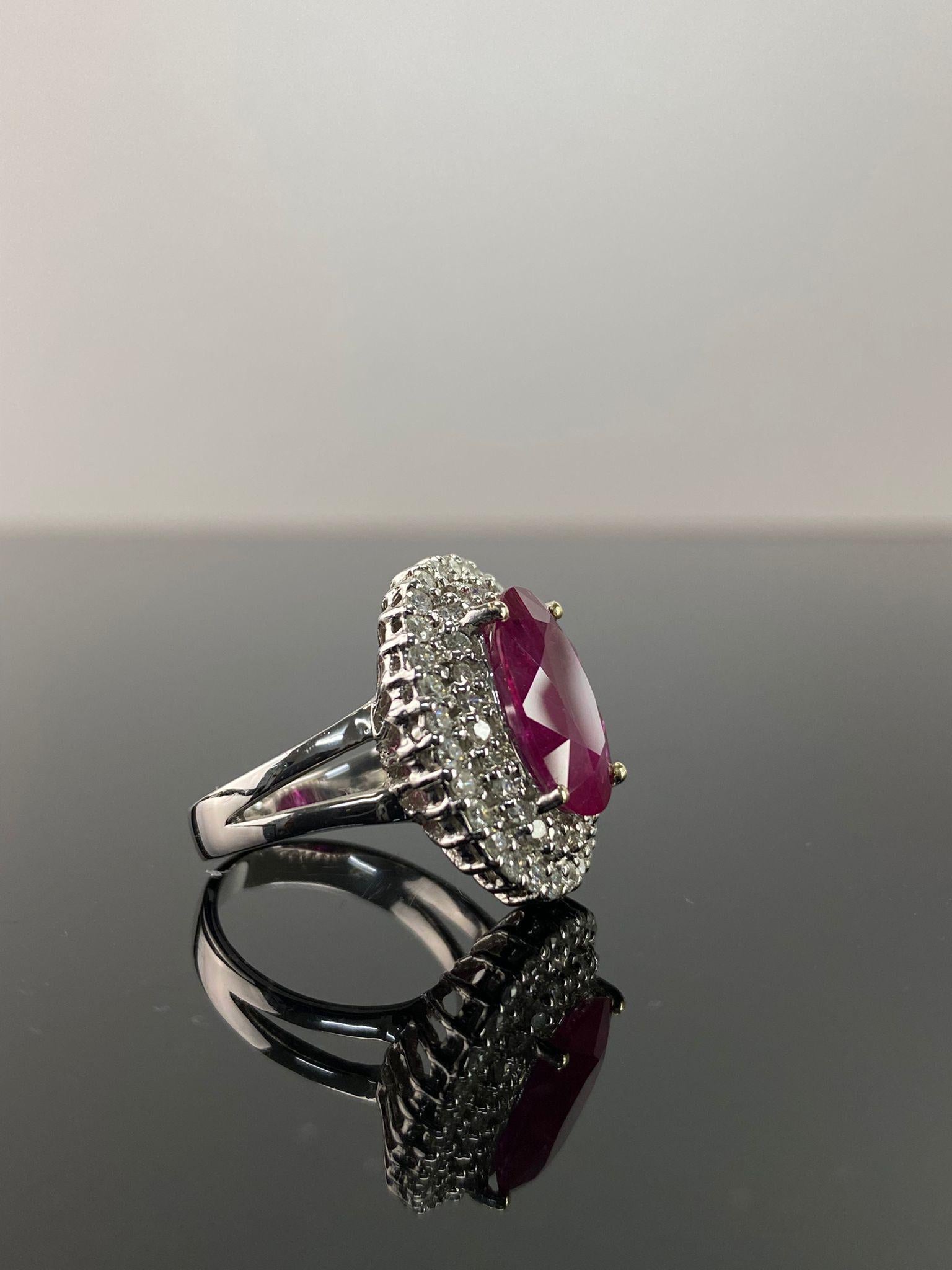 A classic 5.59 carat oval shaped natural Ruby cocktail engagement ring, with 1.33 carat of White Diamonds surrounding it. The beauty of the ring lies in the center stone, the long oval Mozambique ruby has an ideal vivid red color, transparent with a