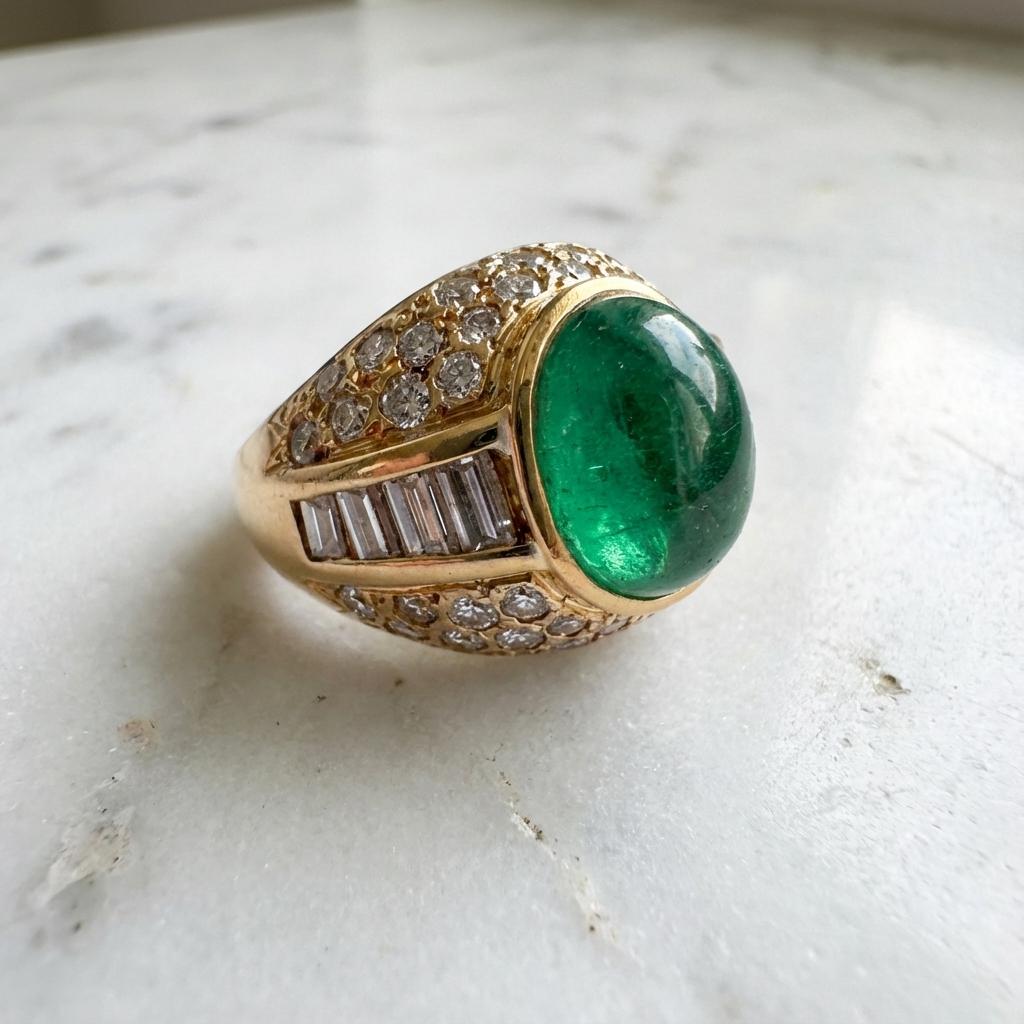 Cette magnifique bague met en valeur une émeraude colombienne d'environ 5,90 carats, présentée dans une audacieuse et luxueuse monture en or jaune 18 carats. L'émeraude, taillée en cabochon lisse, présente une saturation verte vive et une présence