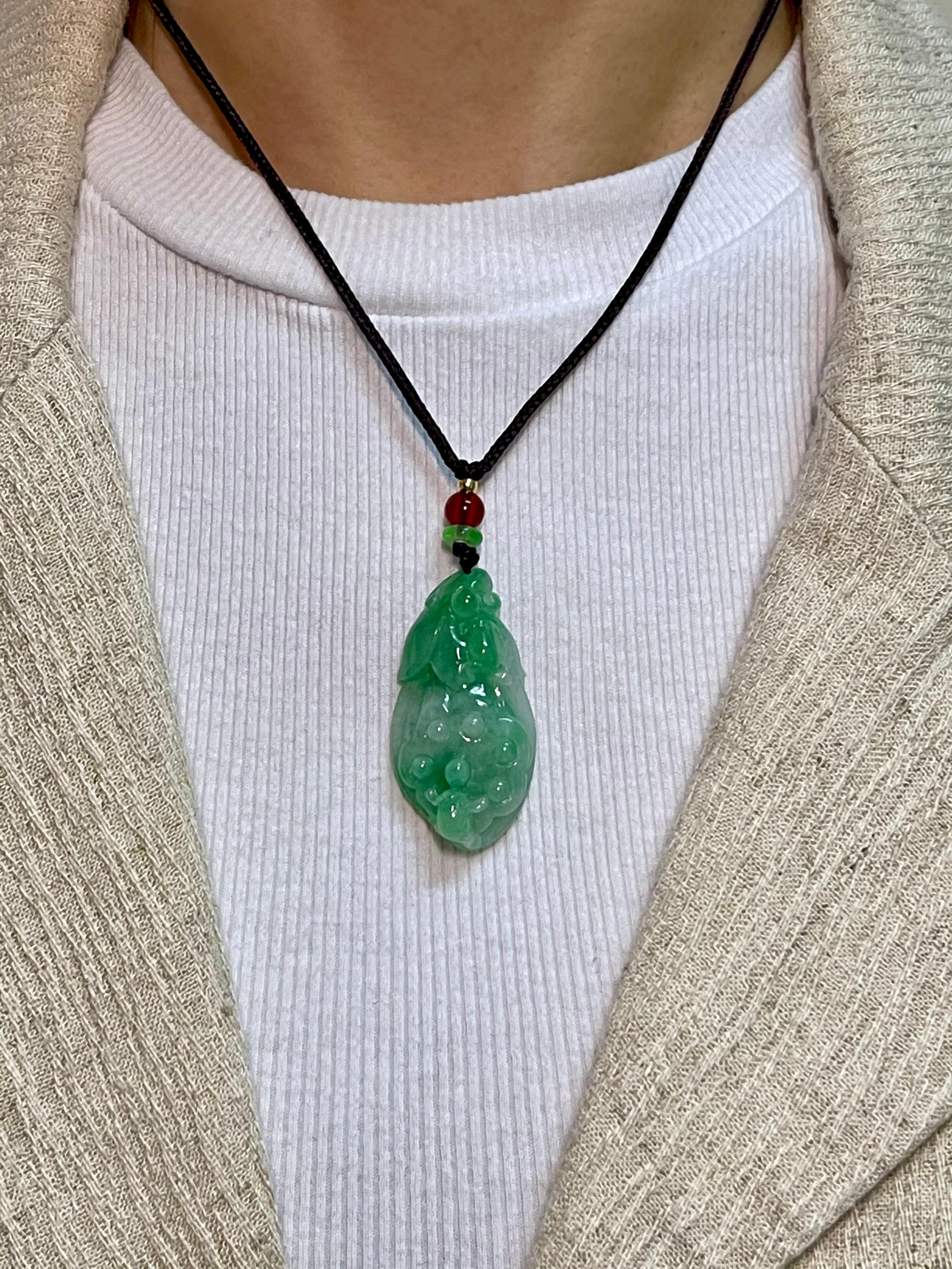 Please check out the HD video. This is certified natural jadeite jade by two labs. The jade carving depicts a Chinese vegetable which symbolizes fertility and abundance like a harvest. The apple green jade and red bead are held together with a