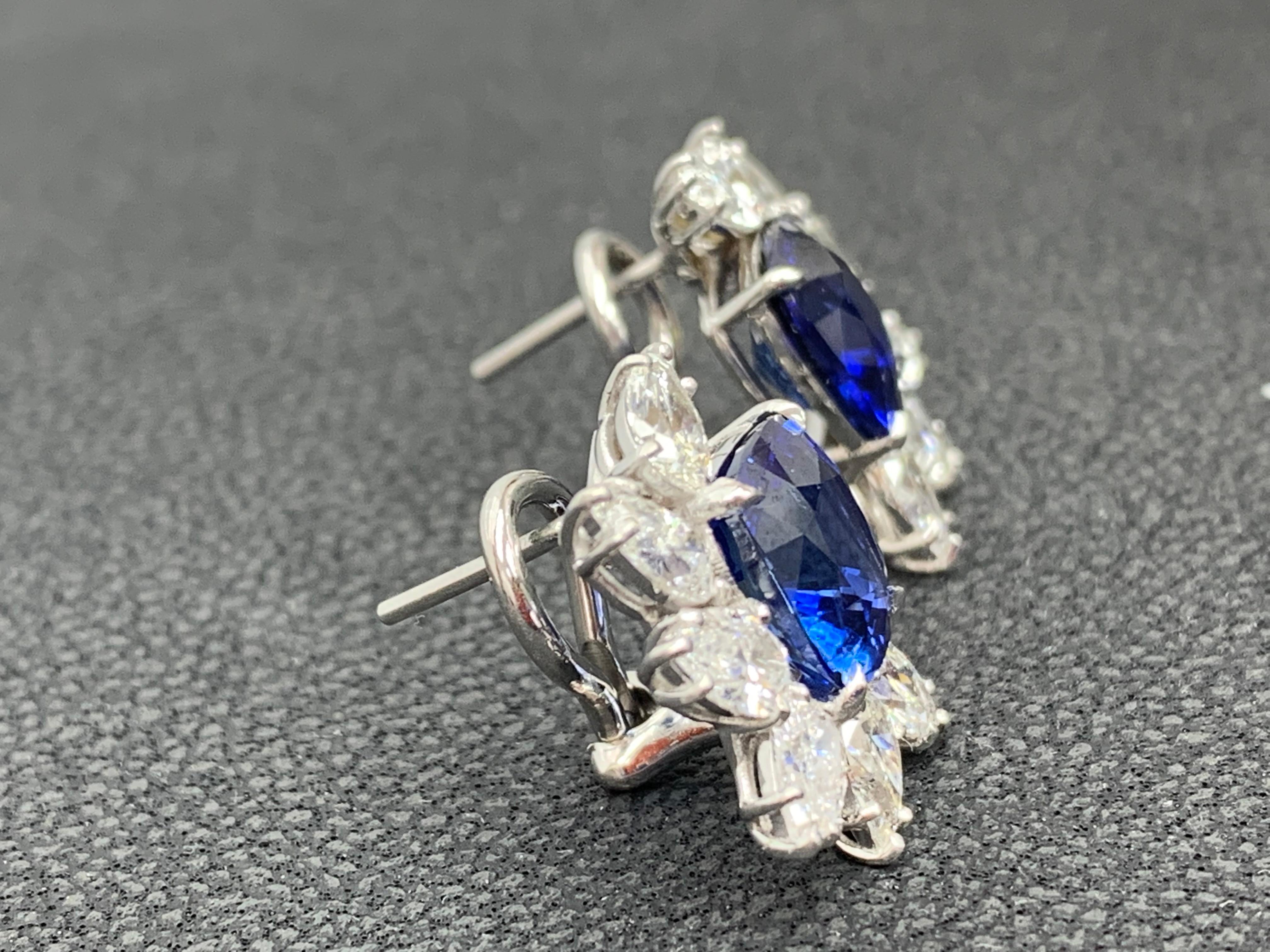 A simple and fashionable pair of Certified earrings showcasing a cluster of pear shape diamonds surrounding Cushion cut Blue Sapphire halfway, set in a beautiful design made in 18k white gold. Blue Sapphire weighs 7.55 carats in total. 12 Diamonds