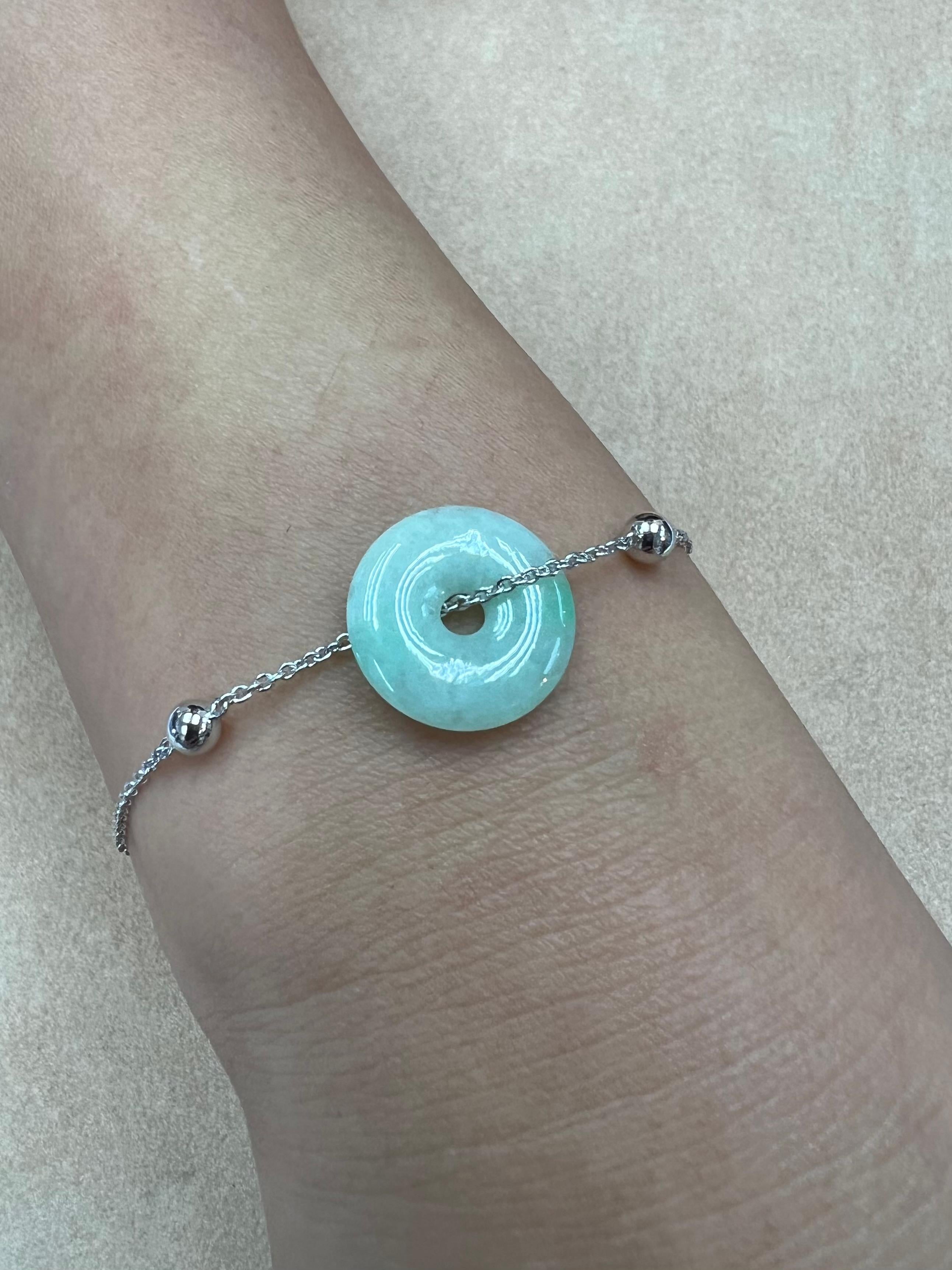 Please check out the HD video. This is certified natural jadeite jade. The bracelet is set in 18k white gold. The jade donut (6.94cts) is light green with patches of bright apple green. The untreated / un-enhanced natural jade in this bracelet is