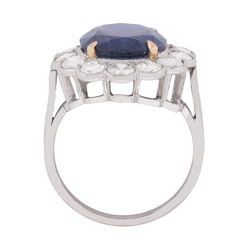 A remarkable 7.40 carat, transparent blue, oval-shaped natural sapphire showing no evidence of enhancement. This is wrapped within a scalloped border of transitional cut diamonds, which also cascade down the shoulers of the ring. 
This stunning