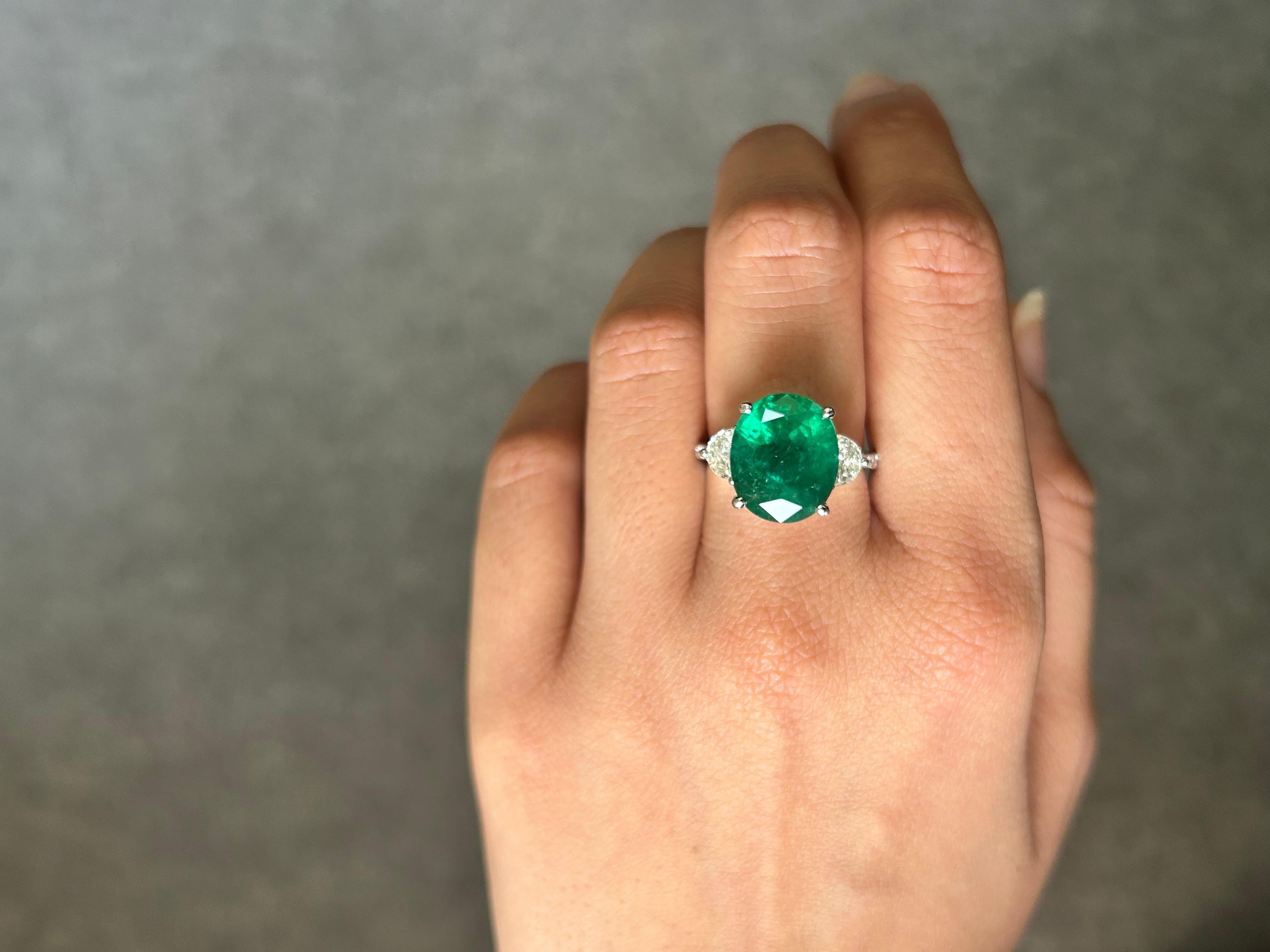 Magnifique bague de fiançailles à trois pierres en émeraude naturelle de Zambie de 7,12 carats de forme ovale, avec des diamants demi-lune de 0,62 carat et des diamants ronds de 0,13 carat sur le bracelet. La pierre centrale est de qualité