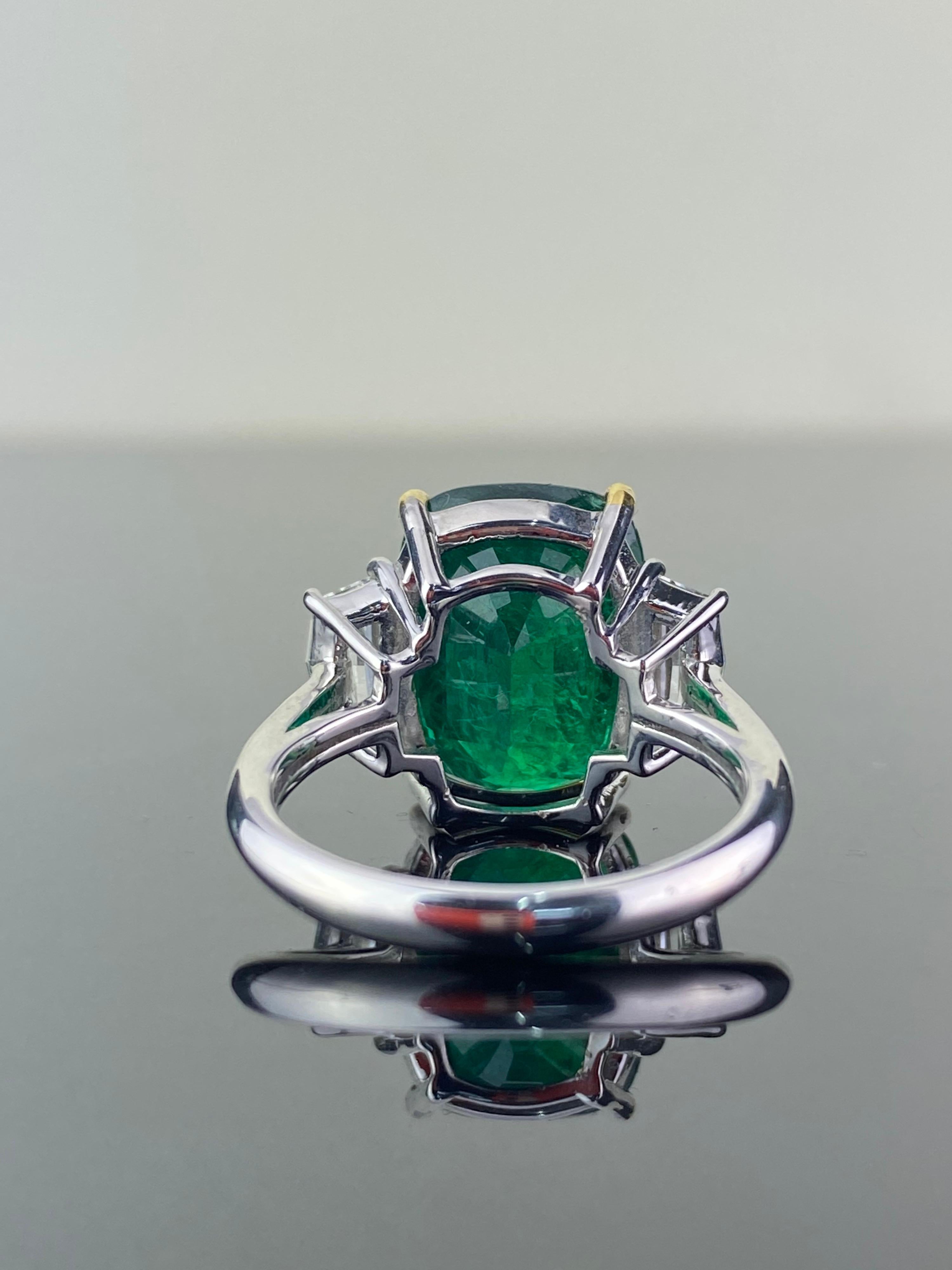 A classic 7.88 carat Emerald and 0.86 carat Diamond three-stone engagement ring. The cushion-shape Emerald is transparent, with a beautiful ideal vivid green color, and is adorned by a pair of special cadillac-cut White Diamonds of VS quality, F