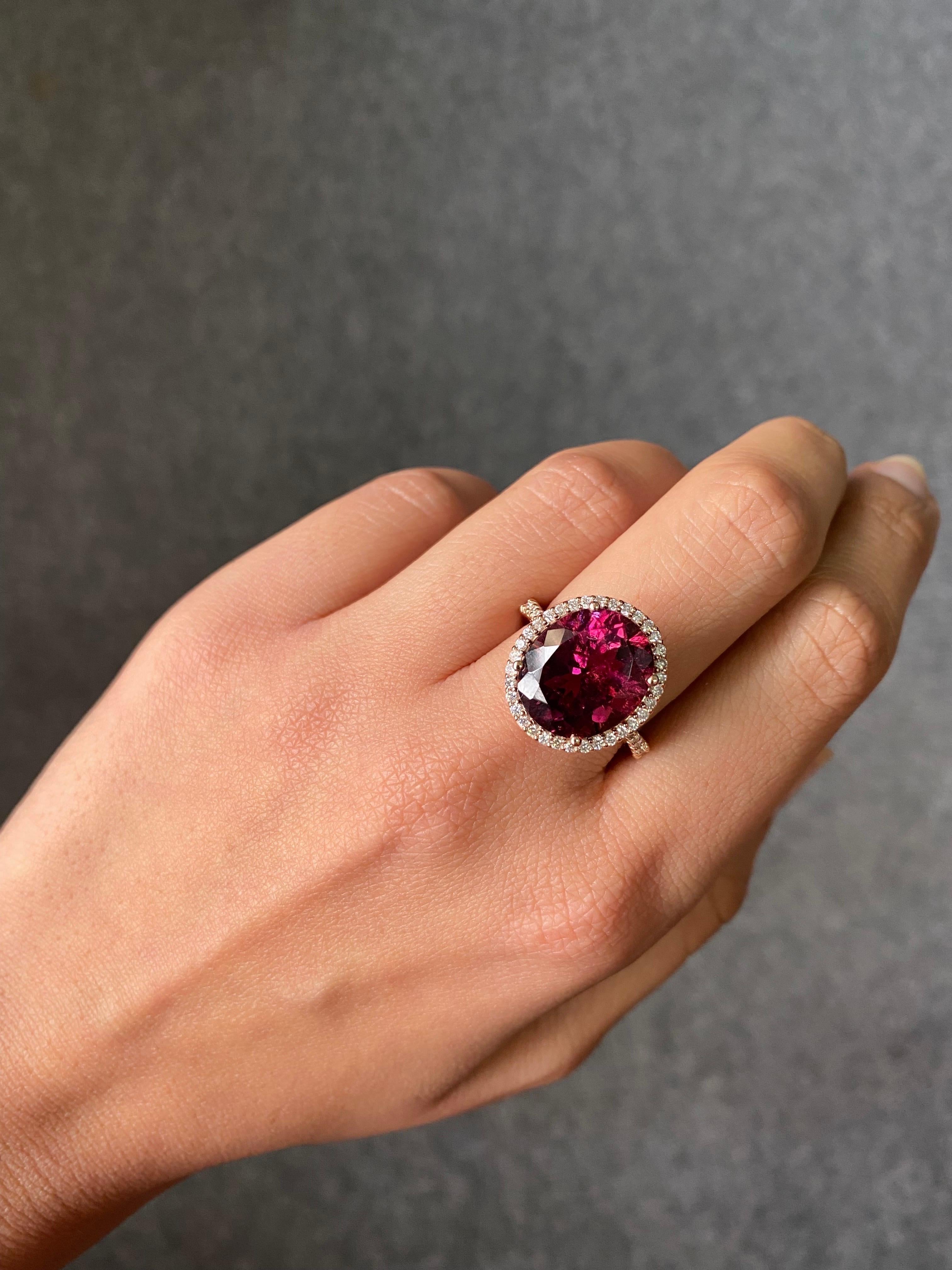 A beautiful, oval shaped 7.95 carat Tourmaline center stone adorned with 0.6 carats White Diamonds, all set in solid 18K Rose Gold. The Tourmaline is of an eye-catching deep pink color, and amazing luster. The ring is currently sized at US7, can be