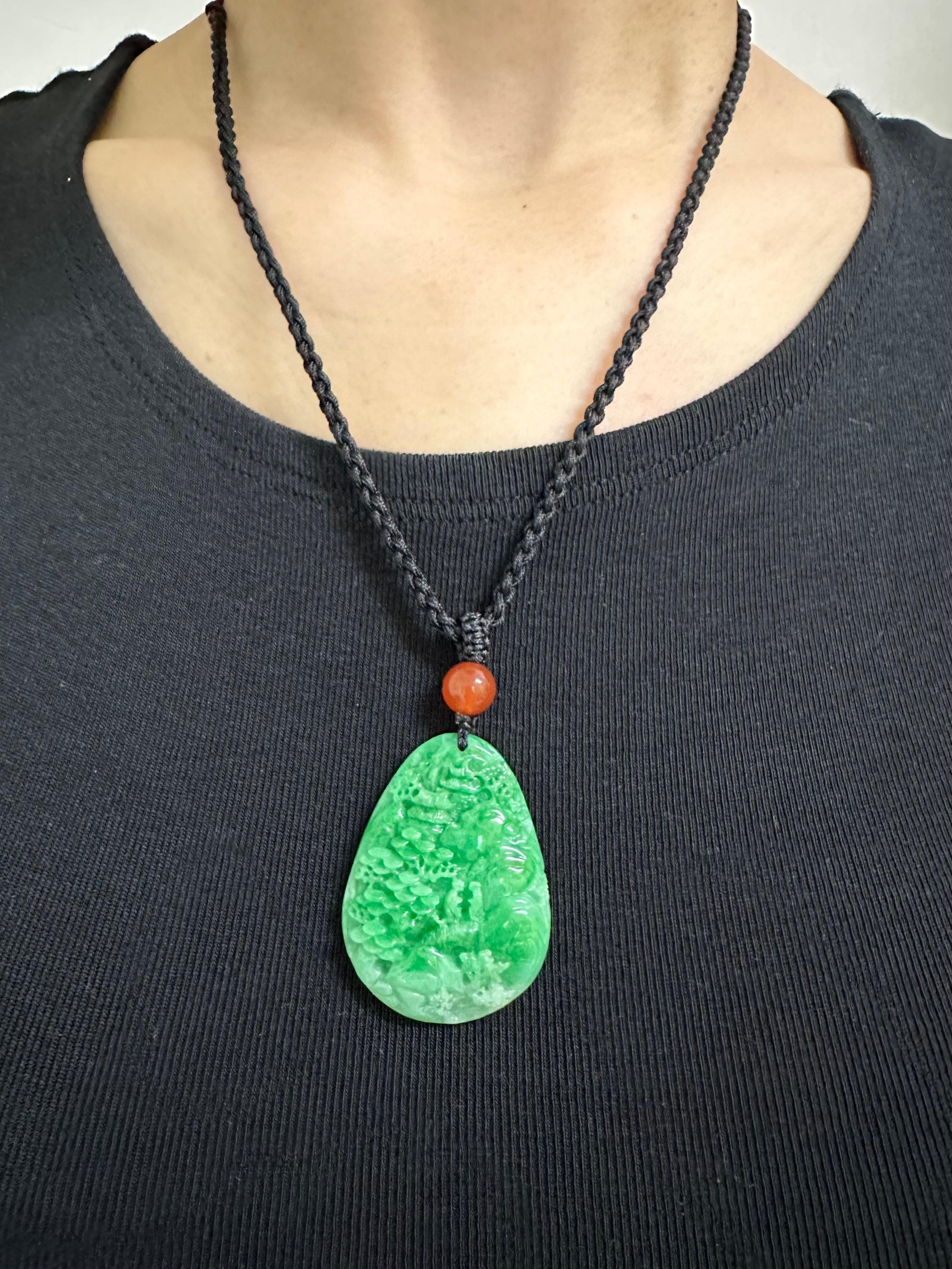 Please check out the HD video. This is certified natural jadeite jade. The jade carving depicts a Chinese scenic mountain. Masterful carving is on both sides of the jade pendant. The apple green jade and red agate bead are held together with a