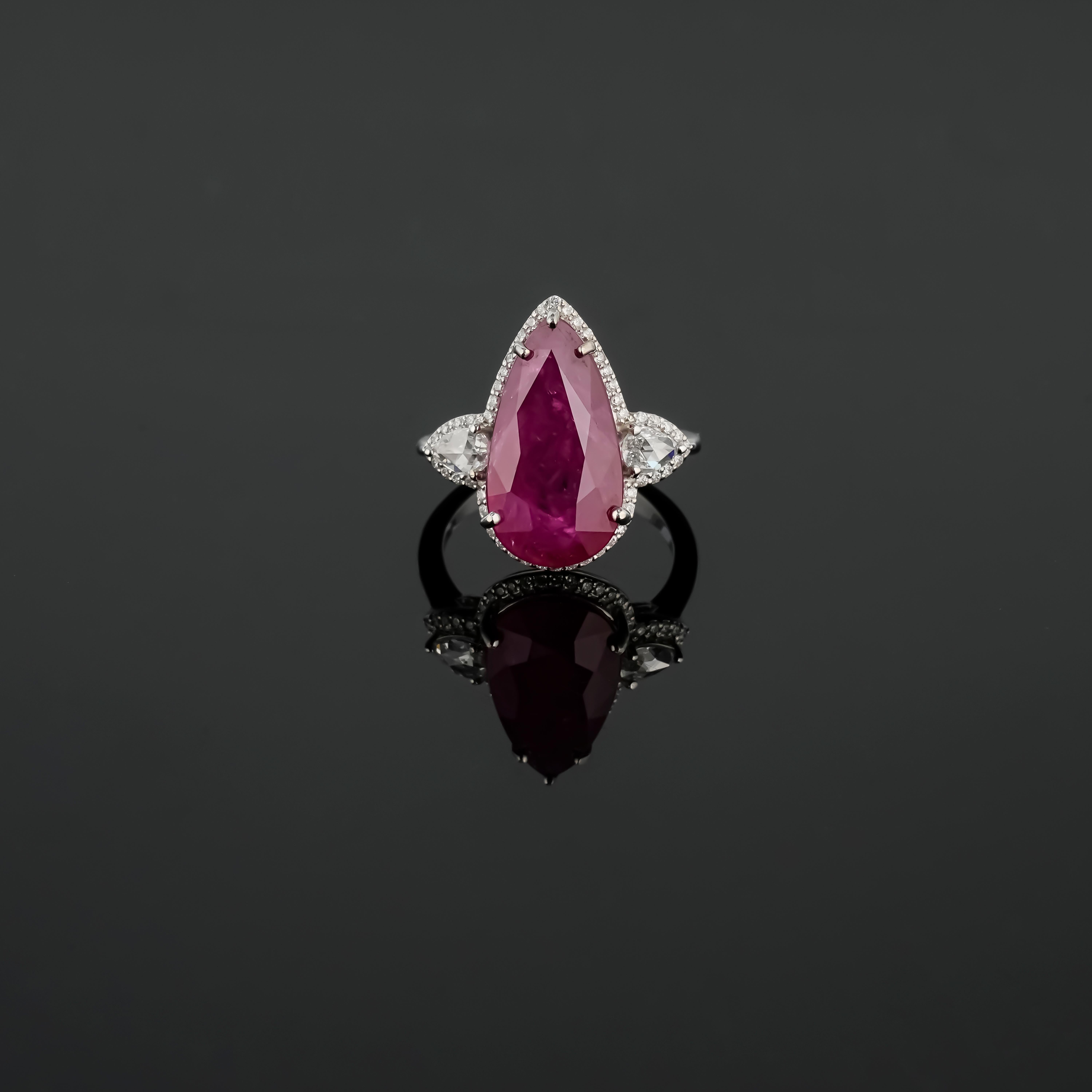 Un impresionante Rubí de Birmania natural certificado de 8.8 quilates, de color rojo vivo y transparente. La pieza central está adornada con diamantes laterales en forma de pera de 0,38 quilates, calidad VS, color G, y diamantes redondos de 0,30
