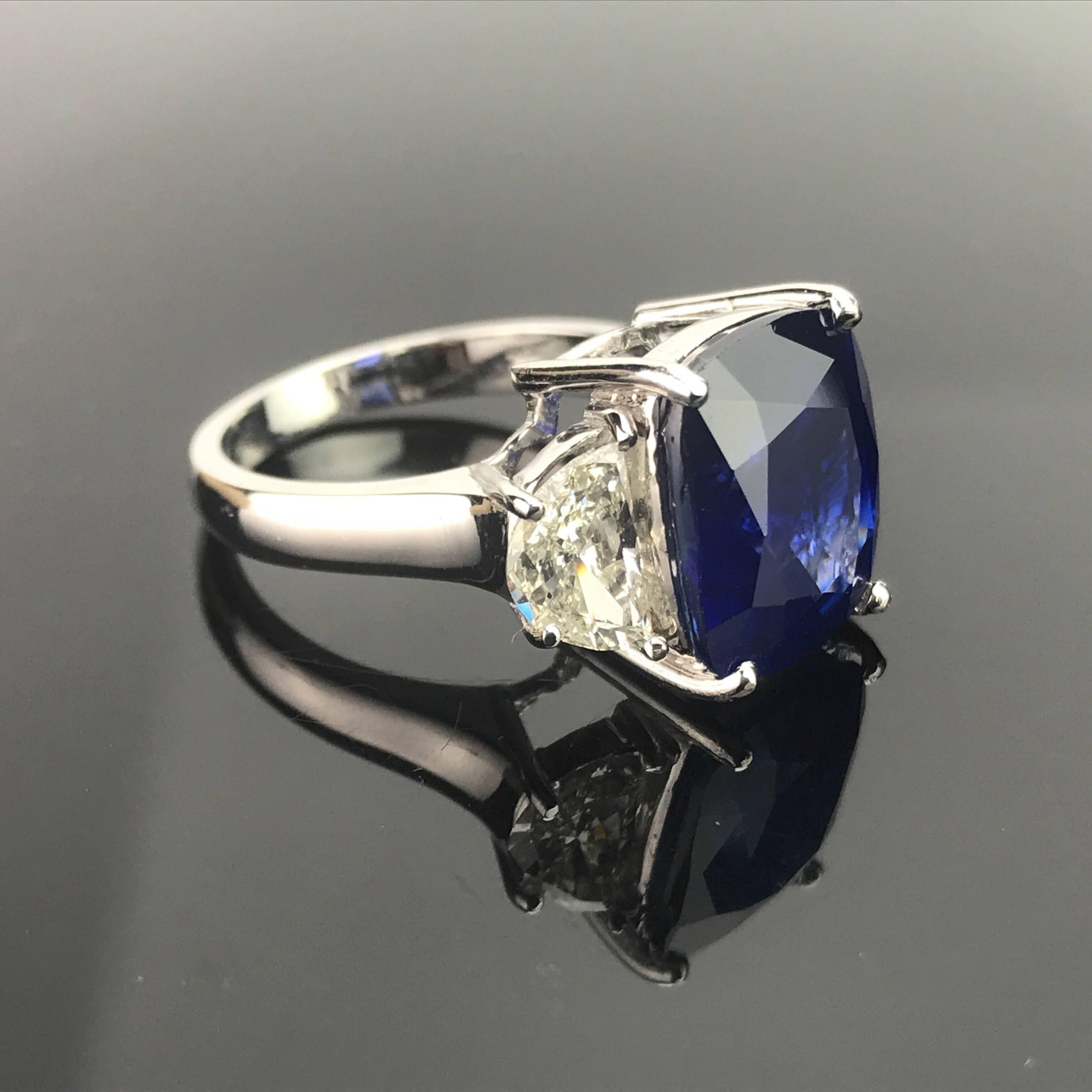 A classic 3-stone ring, with a cushion-shaped eye-clean Sri Lankan Sapphire and 2 half-moon (0.7 carats each) diamonds on each side. 

Stone Details: 
Stone: Blue Sapphire
Carat Weight: 8.80 Carats

Diamond Details: 
Total Carat Weight: 1.41