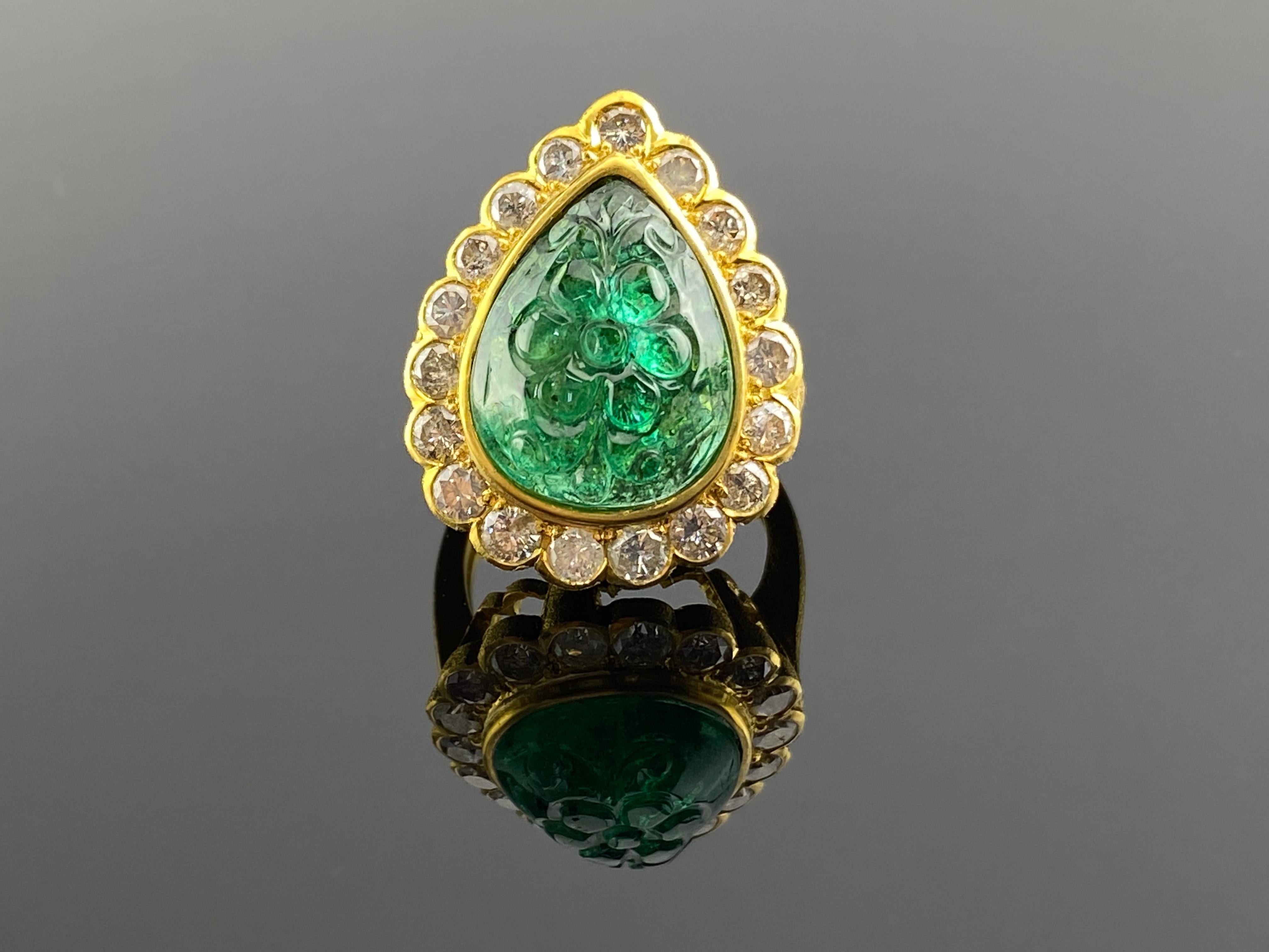 This magnificent Emerald and Diamond cocktail ring is crafted in solid matte finish 18K yellow gold. The impressive ring is centered with a genuine Zambian carved floral Emerald weighing 11.46 carat, bezel set. The high polished band is accented by