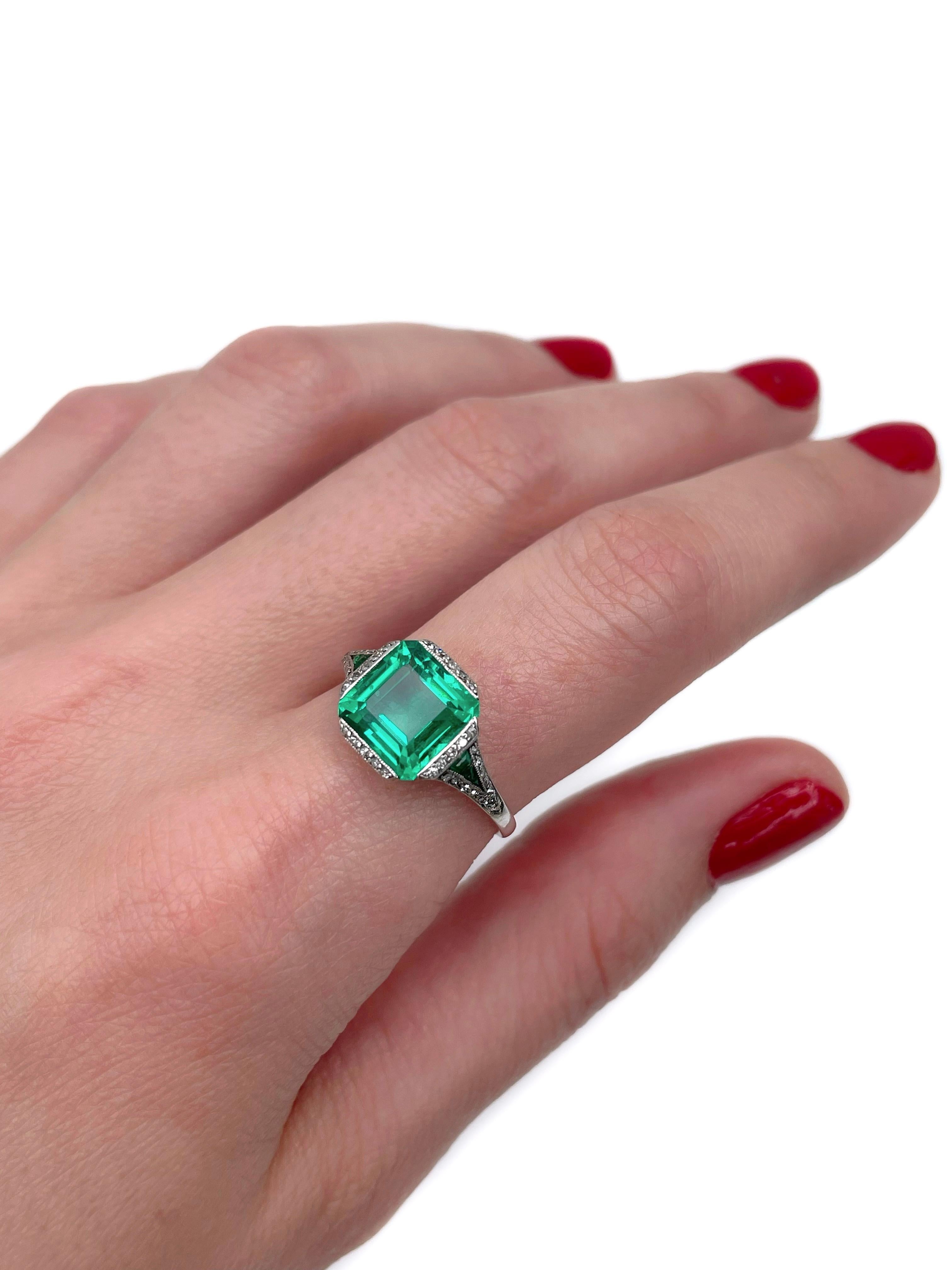 This is a magnificent  Art Deco engagement ring crafted in palladium (Pd 500). Circa 1930.

The piece features an amazing VVS clarity vivid green colour natural emerald. The gem is accompanied with smaller emeralds (TW 0.05ct) and old cut diamonds