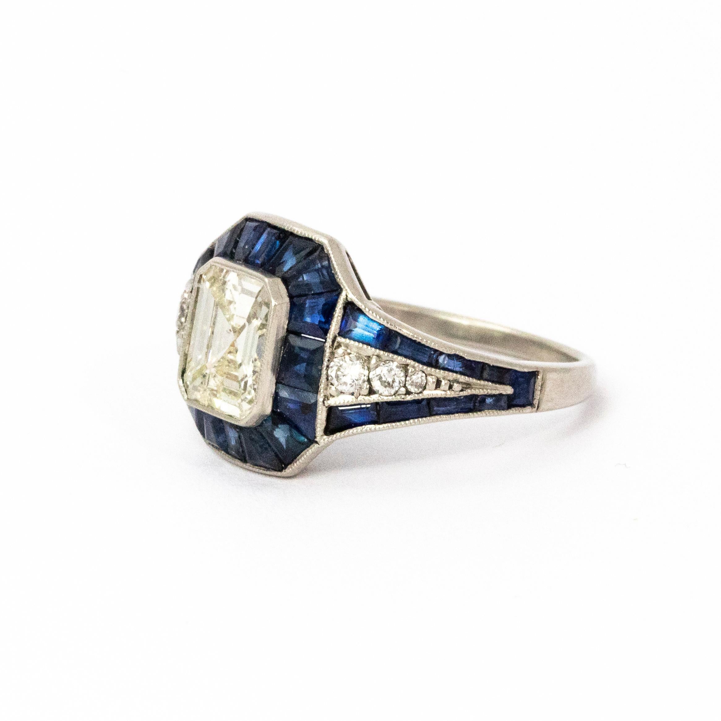 Absolute show stopper! This stunning ring has a centre emerald cut diamond weighing 1.74 carats, colour J SI-1 and is surrounded by beautiful sapphires totalling 1.28 carats and set in platinum. 

Ring Size: N or 6 3/4