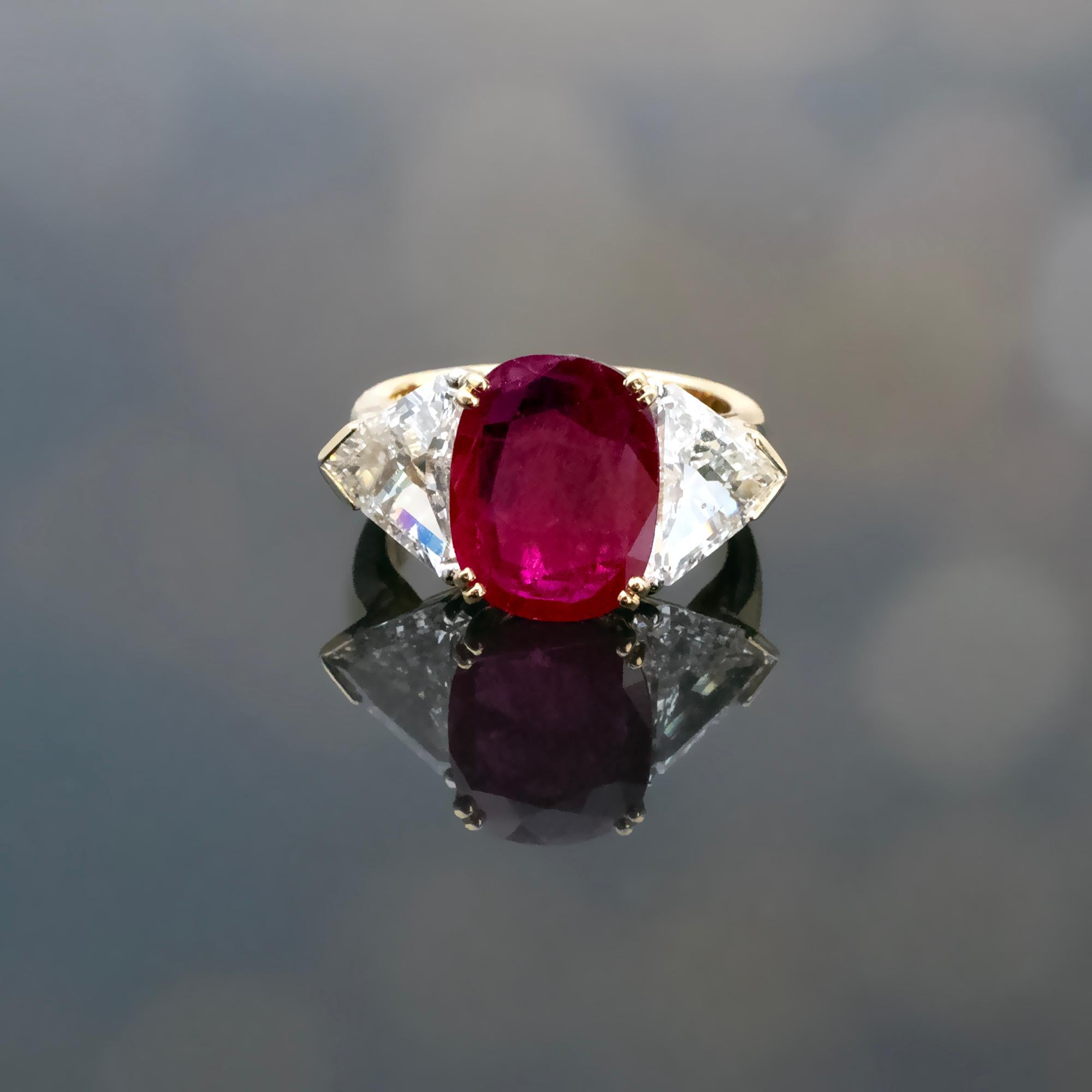 Este impresionante anillo trilogía exhibe un rubí natural ovalado de talla cojín, de 2,62 quilates, procedente de Birmania (Myanmar), famosa por producir algunos de los rubíes más finos del mundo. El rubí muestra un vibrante tono rojo intenso, con