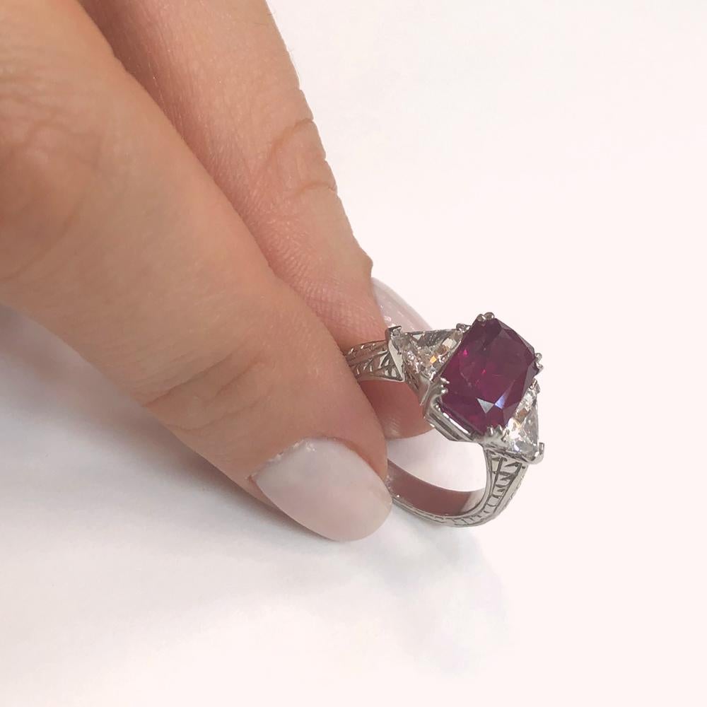 Handcrafted engraved gemstone ring holds a Burmese red cushion cut ruby 3.60 ct center stone.
Burma ruby is Certified.
It is accented at either sides with triangle cut natural diamonds 0.93 ct in G-H Color Clarity VS on a platinum 950 metal