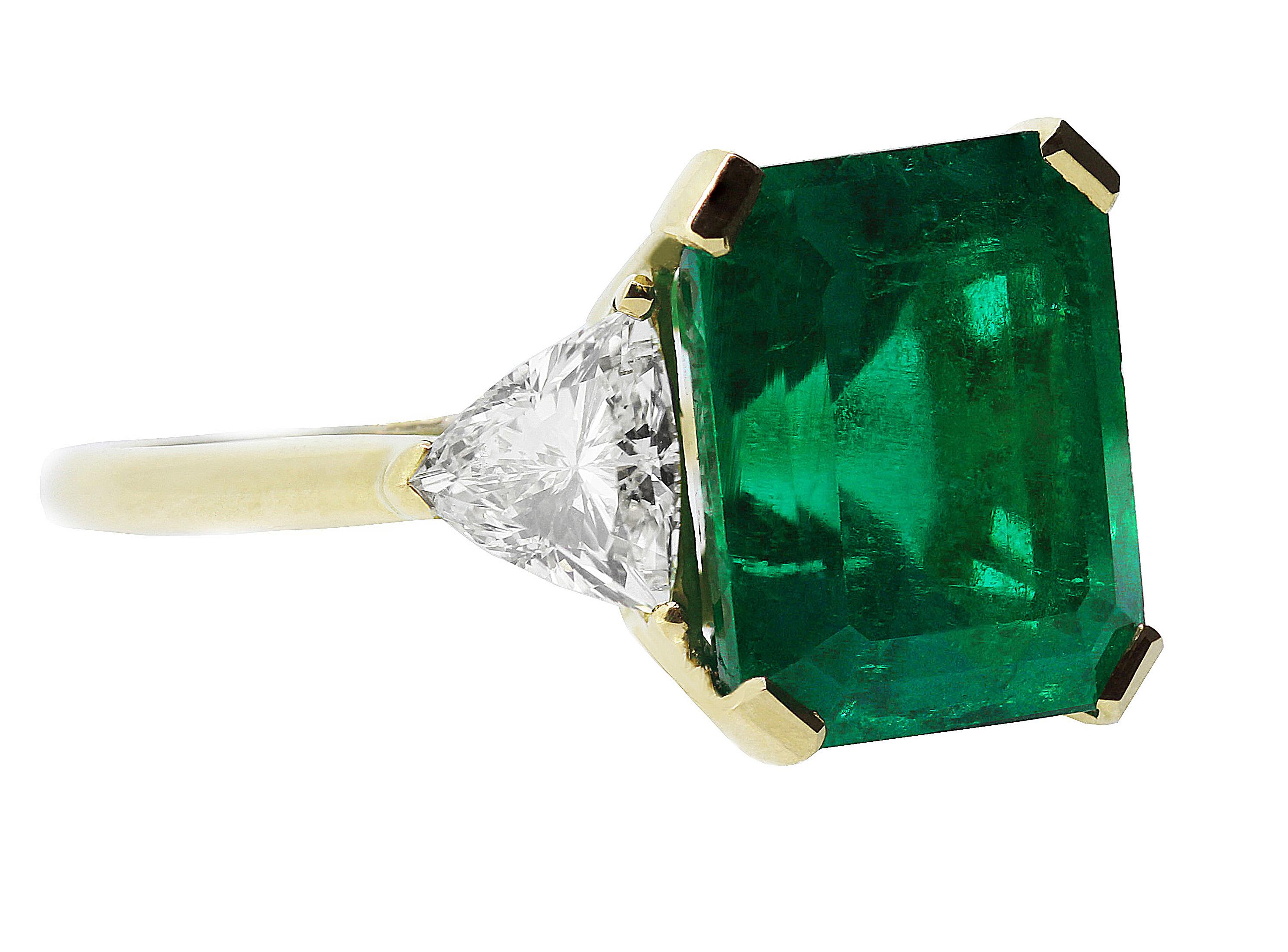 This impressive vintage emerald with the most beautiful emerald green colour and diamond three stone ring is crafted in solid 18 K yellow gold.  A magnificent 7.75 ct certified Colombian emerald and it is flanked by 2 sparkling triangle bulged side