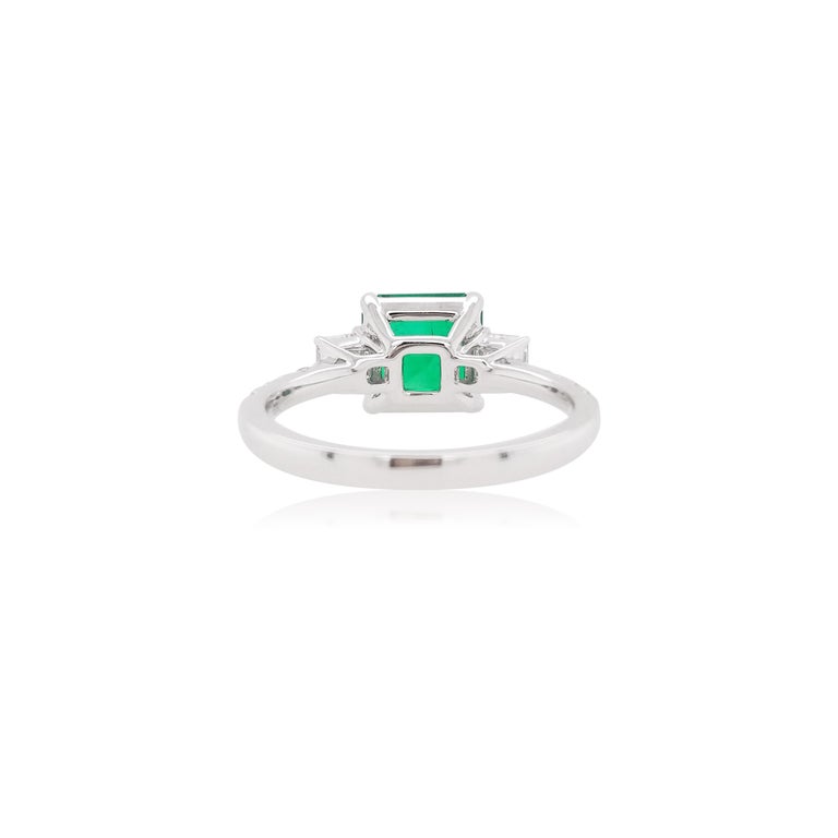 This striking ring features an exceptional Colombian Emerald at its centre, flanked by two Asscher-Cut White Diamonds. The ring is made of 18 Karat White Gold to provide a unique, and elegant contrast to the rich color of the Emerald. This