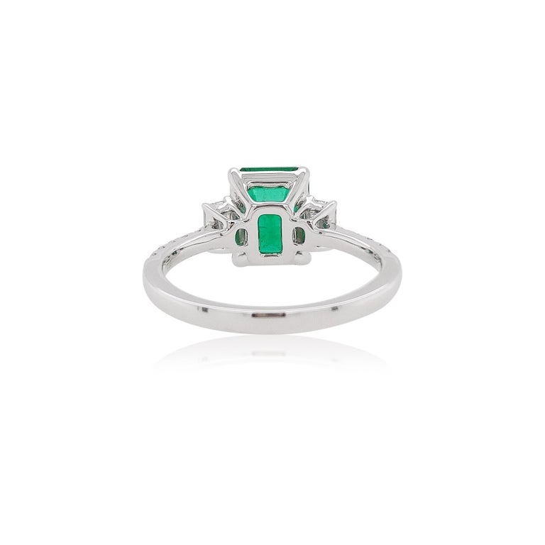 This delicate 18 Karat White Gold ring features a lustrous Colombian Emerald at the forefront of its design. The spectacular hues of the Emerald are perfectly accentuated by the White Gold setting and elegant Emerald-Cut Diamonds on its shoulders.