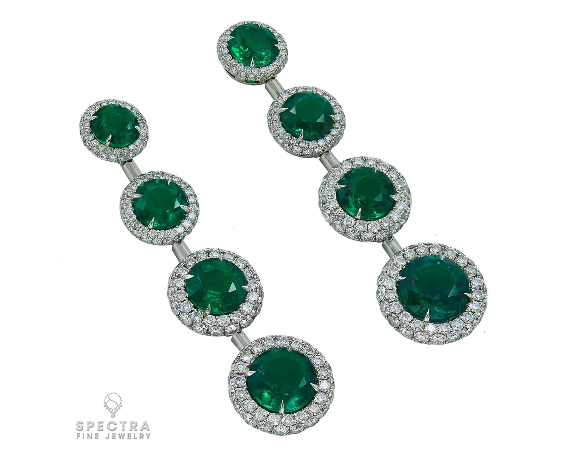 Emeralds are as shimmering and magical as new growth in Spring and these Contemporary Colombian Emerald Diamond Halo Graduated Drop Earrings, made in the 21st century, feature the verdant stones in all their glory. The resplendent pair of drops is