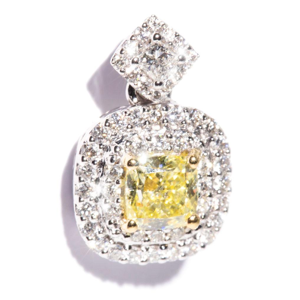 Lovingly crafted in 18 carat white gold is this gorgeous contemporary design pendant featuring a certified Light Fancy Yellow cushion cut diamond embellished with a double halo of round brilliant cut diamonds, and a glittering princess cut diamond. 
