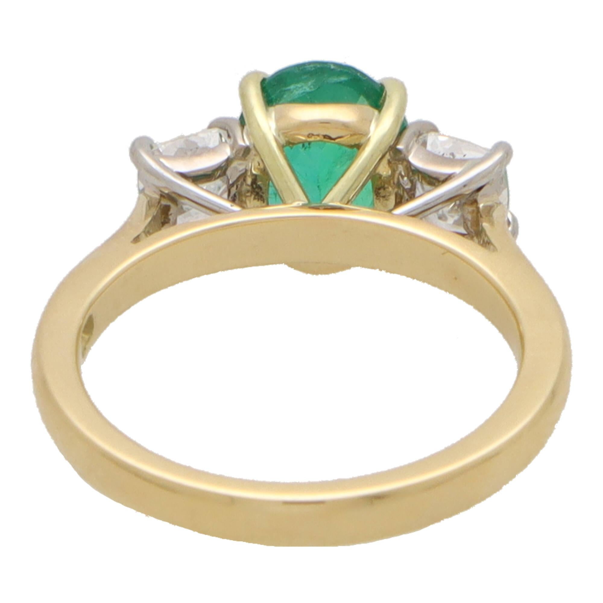 A beautiful emerald and diamond trilogy ring set in 18k yellow and white gold.

The three stone is centrally set with a vibrant oval cut emerald which is four claw set in an open back gold triple setting. The emerald is then flanked to each side by