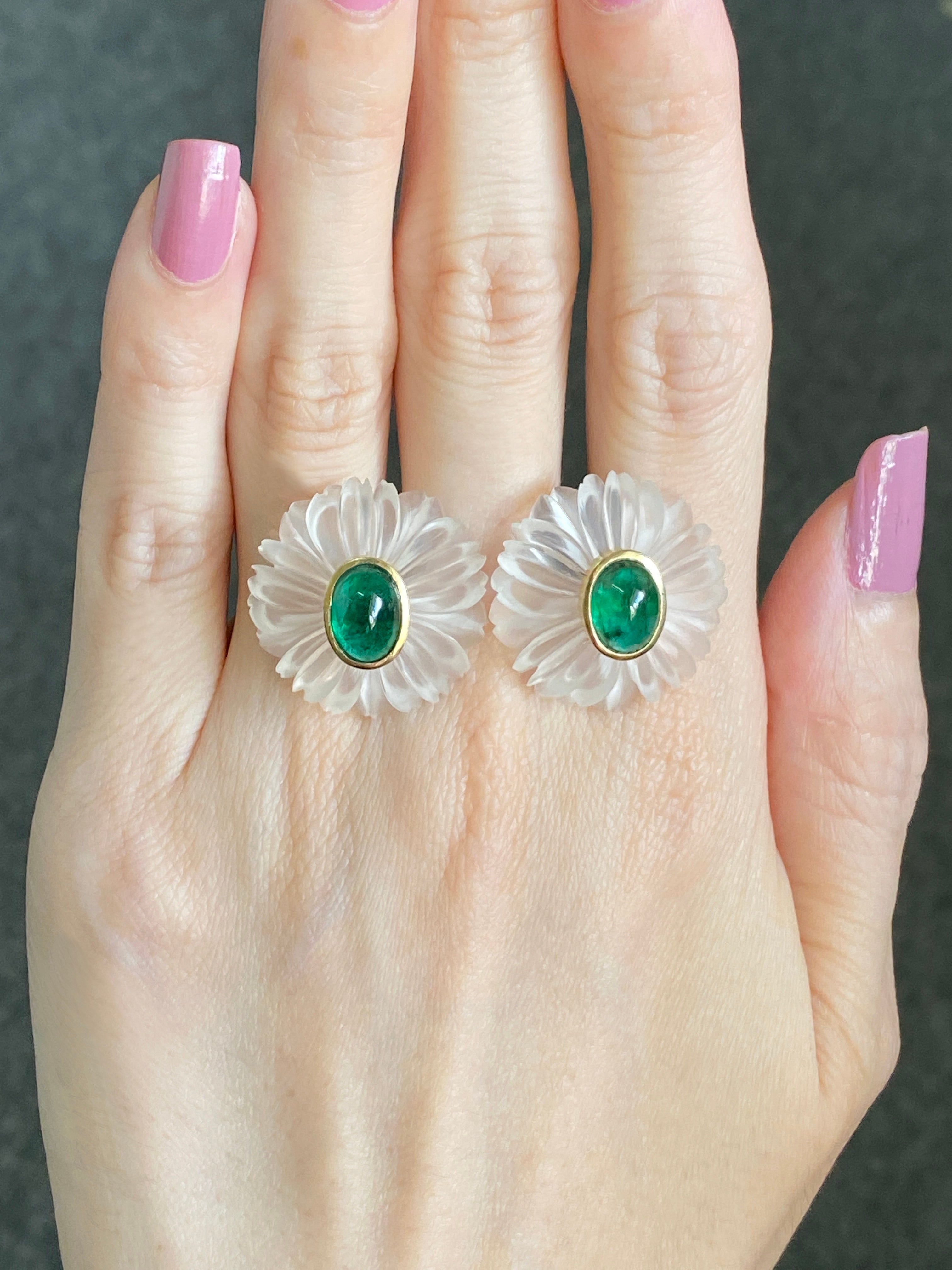 A pair of flower shaped carved rock crystal earrings with emerald cabochon, bezel set in the centre with 18K yellow gold . These are an elegant pair of earrings with the finest hand carved work being put in them to create the carvings . The total