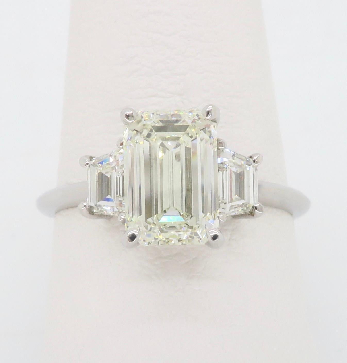 Clásico anillo de compromiso de diamantes talla esmeralda con dos diamantes trapezoidales flanqueando la piedra central. 

Peso en quilates del diamante central: 2.01 quilates
Centro talla diamante: Esmeralda 
Color del diamante central: J 
Claridad