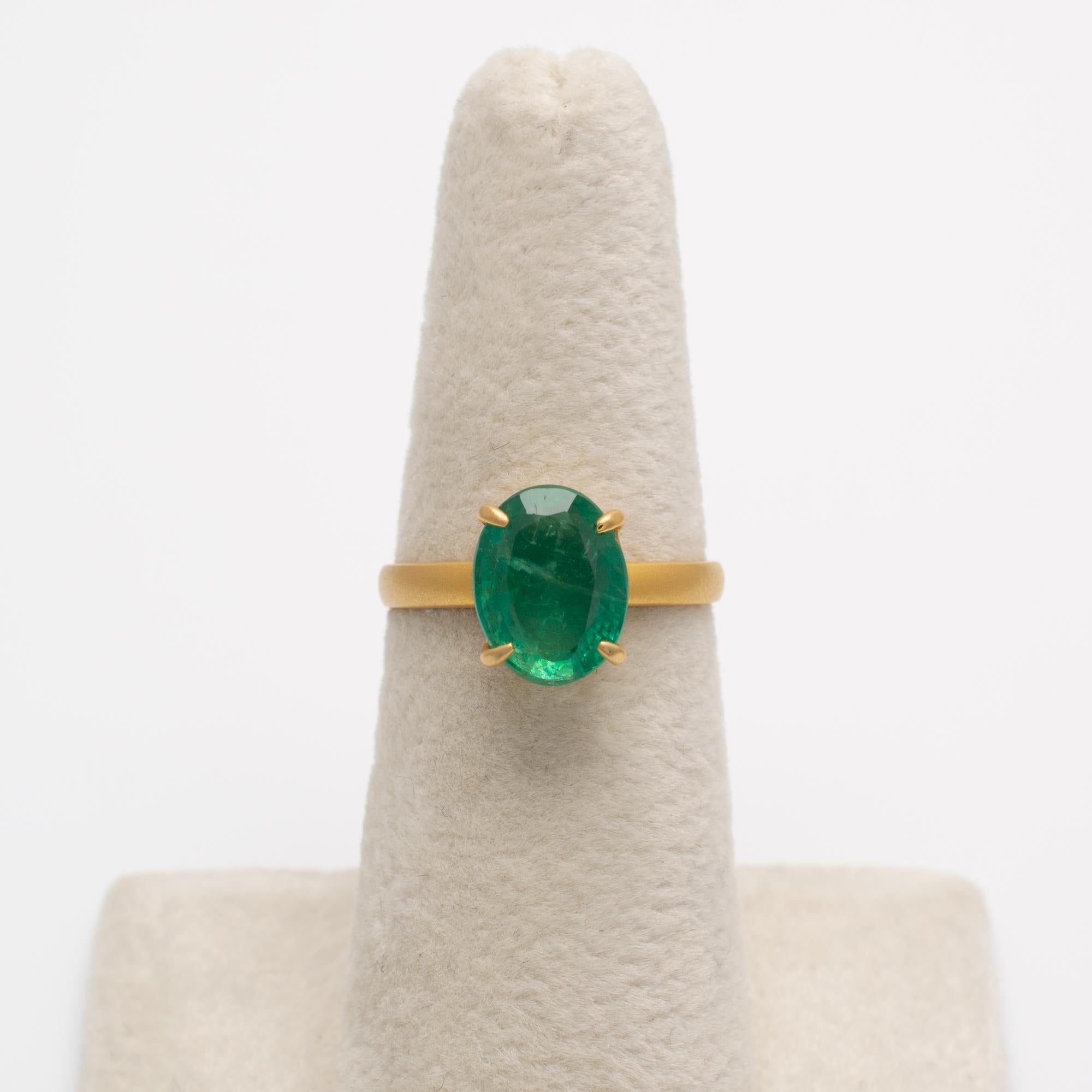 This natural oval-cut emerald solitaire ring is made in 18 karat yellow gold with a contemporary matte finish.

The emerald is beautiful in quality with a smooth surface and lovely natural inclusions. We have shown a couple of shots in bright