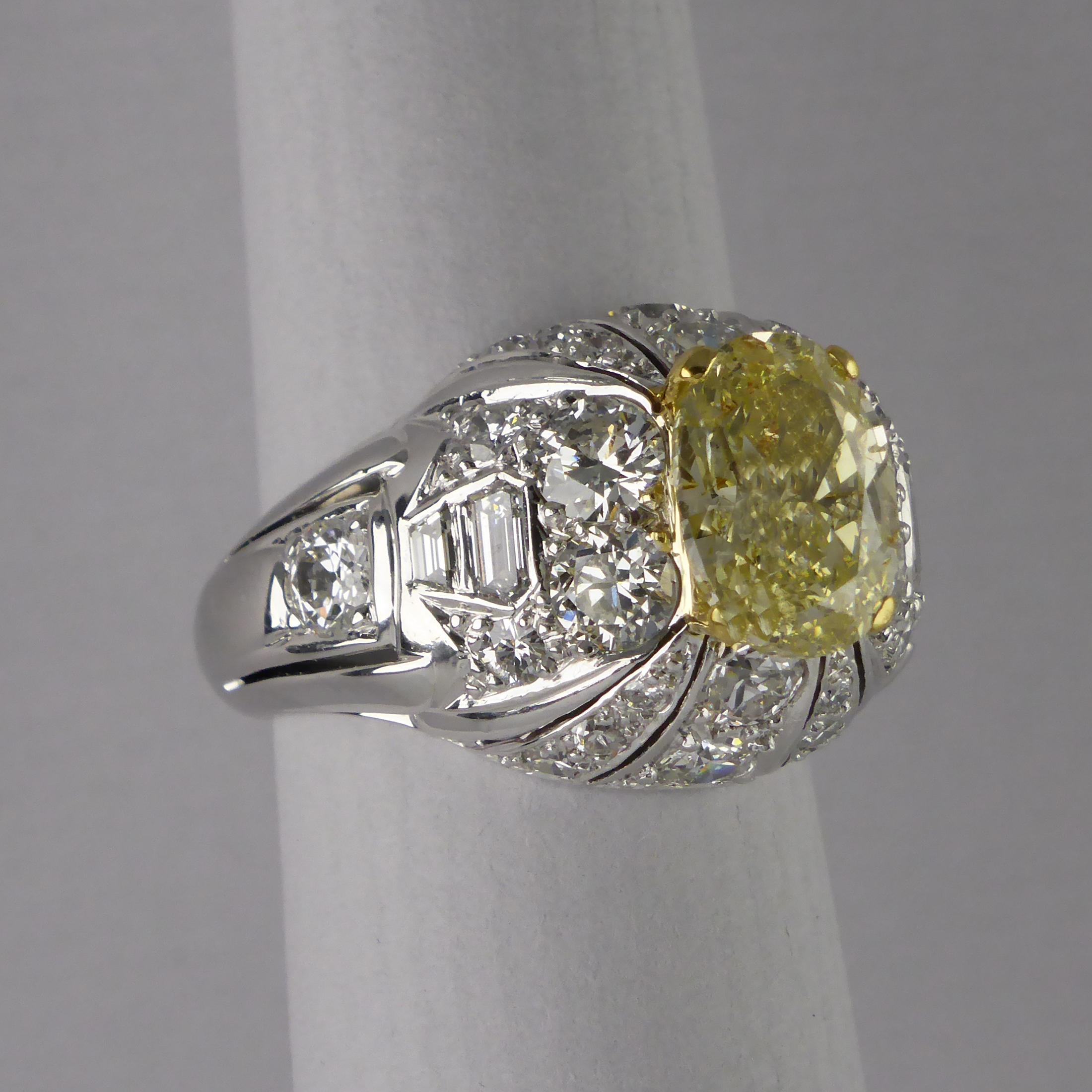 A period bombe ring with a fancy deep canary yellow colour, natural, untreated, diamond surrounded by white diamonds made in circa 1960. 

The diamonds are set in 18ct white gold.

Fancy Yellow Diamond certified weghing 2.11ct and SI2 clarity. Oval
