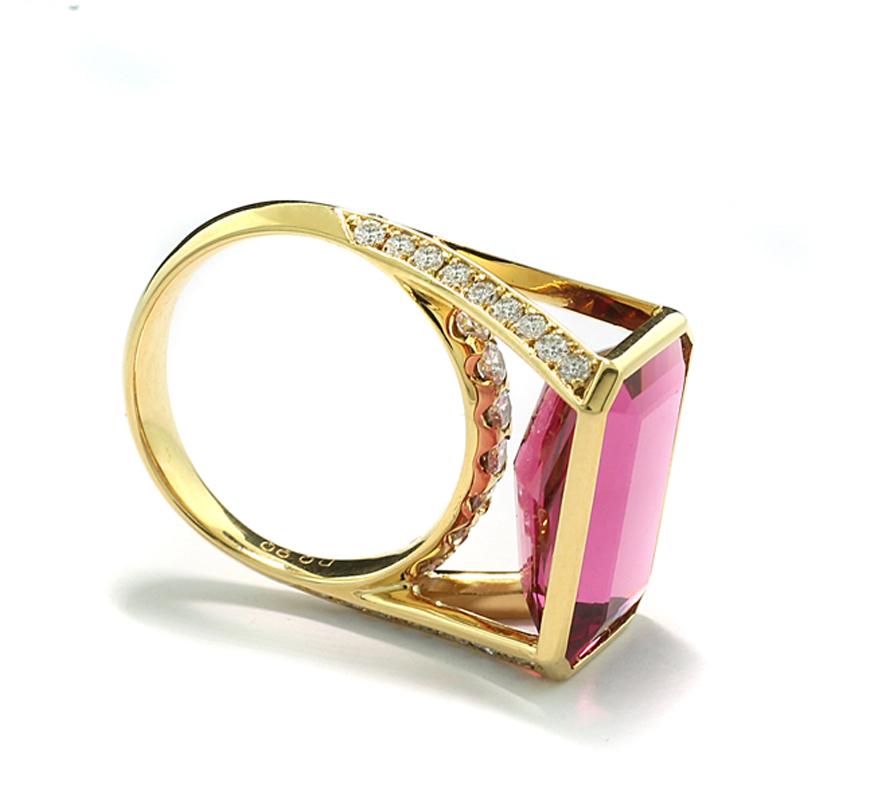 a stunning tourmaline and diamond Ring, displaying a tourmaline weighing approximately 8.46 carats, in an intense pink color, eye-clean quality,  an emerald cut and set in an octagonal setting. The high, split V-shaped shoulders of the ring are set