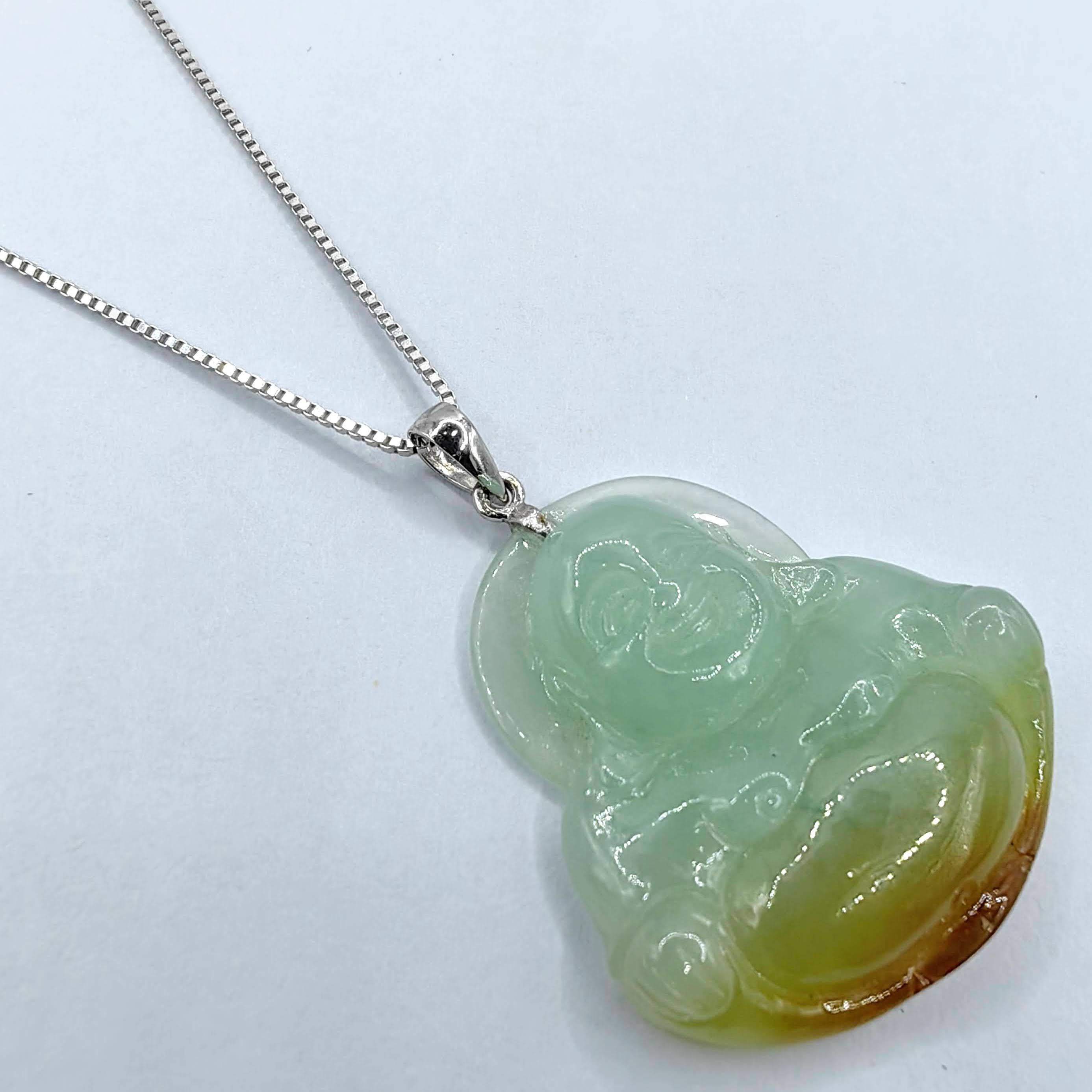 Discover a spiritual masterpiece in this Certified Green & Amber Jadeite Jade Smiling Buddha Pendant, set in luxurious 18K white gold. Skillfully carved from a single piece of light green to amber-brown jadeite jade, this pendant portrays the joyful