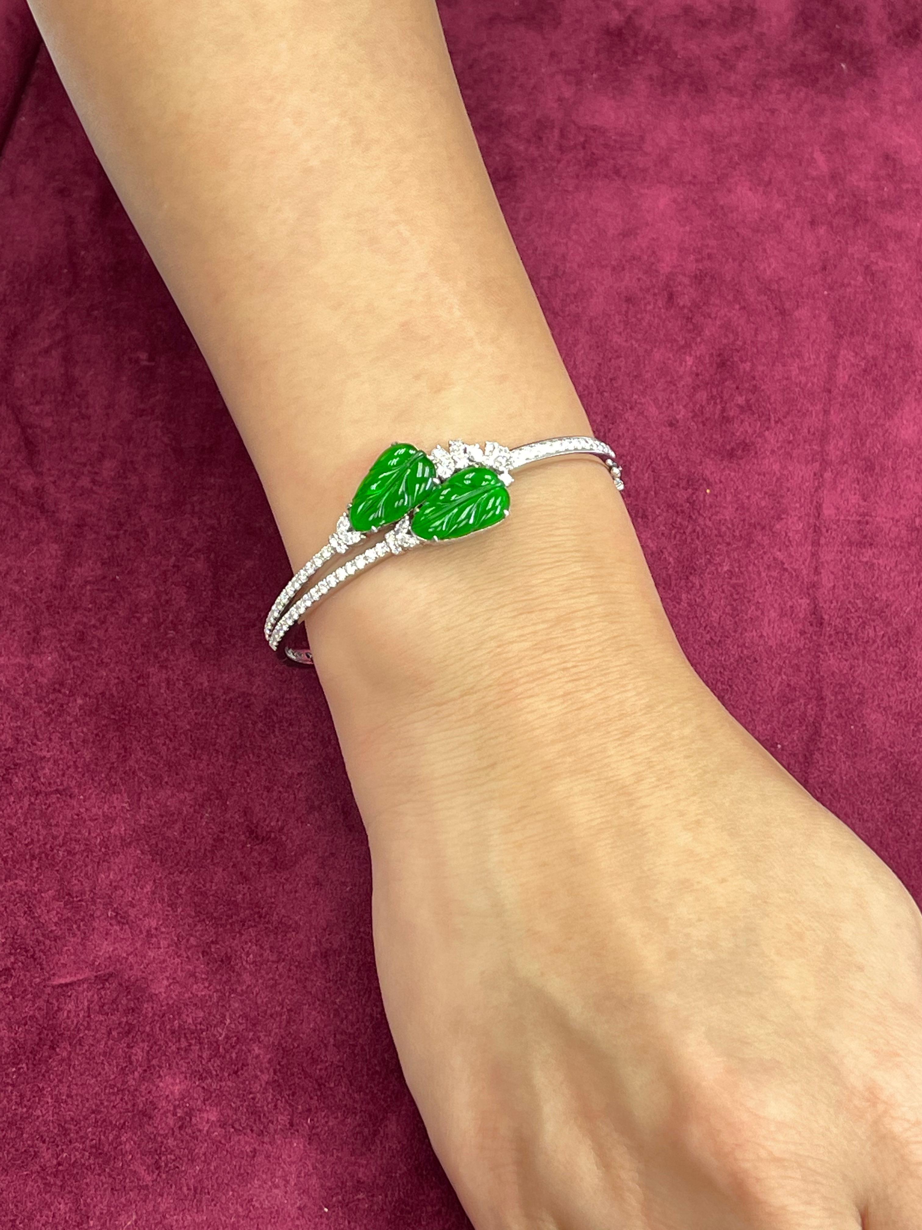 This is certified by two labs to be natural jadeite jade. The bangle bracelet is set in white gold. There are 2 carved apple green jade leaf motifs and 1.517cts of white diamonds. The apple green jade is carved with a leaf motif. The meaning behind