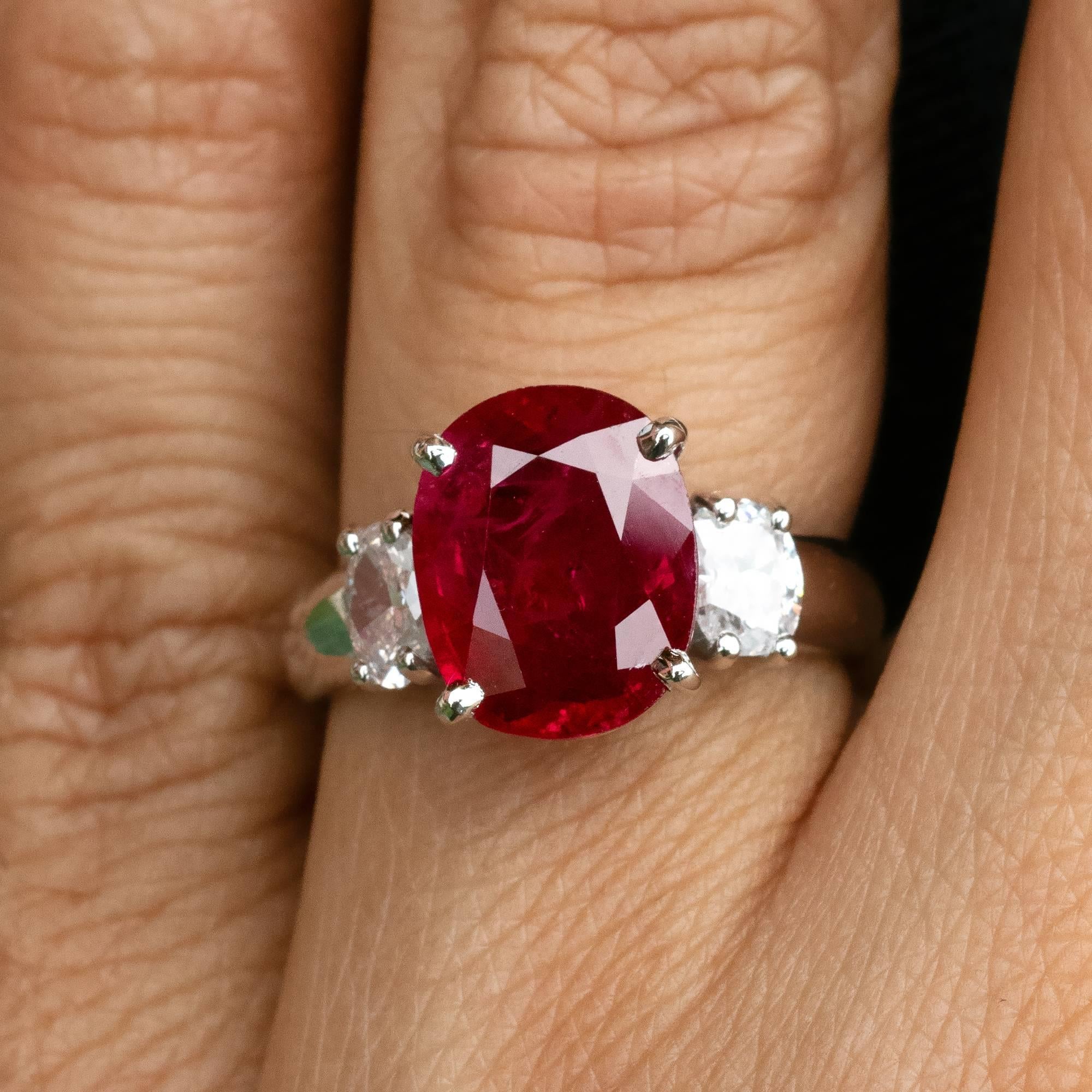 Timeless ruby three stone engagement ring. The center gemstone is a lively 4.10 carat ruby with a real intense red colour.  It is nicely spread and has the appearance of a ruby over 5 carat. Two oval diamonds, weighing  0.69 carat in total and