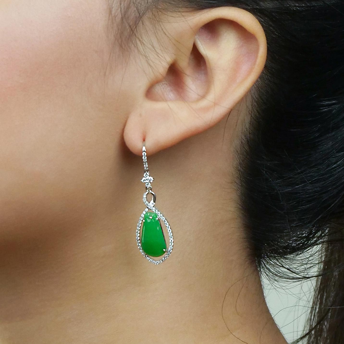 Stunning jade earrings in pear shape dangled by various shapes of crosses, circles and vertical lines all covered in glistening diamonds. The jade is calm and cooling and has a gorgeous sheer glowing sheen on it as well as subtle shades of greens.