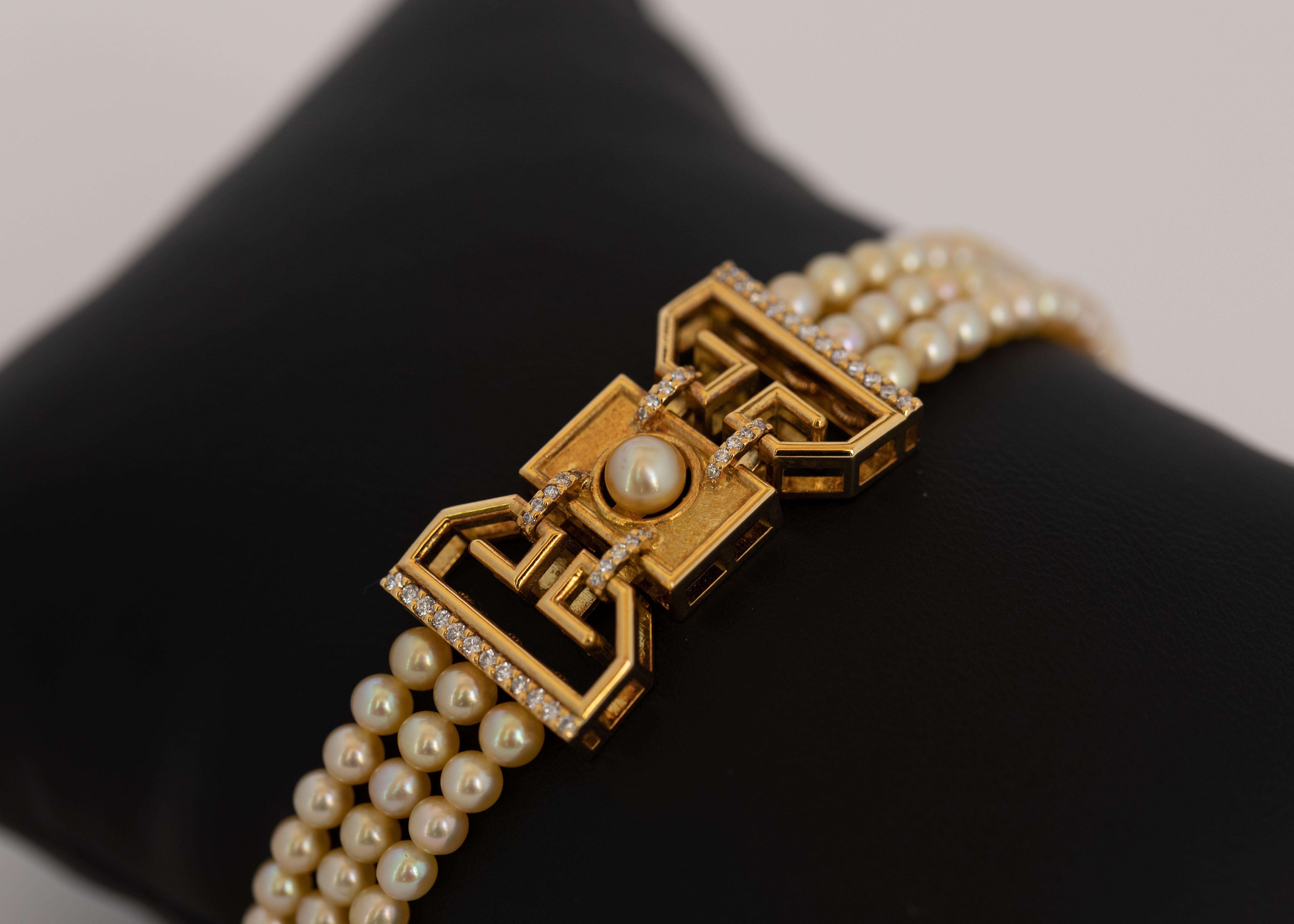3 rows of near round certified dark cream Bahraini natural pearls separated by an 18 karat yellow gold art deco piece.
The motif combines glossy and matte gold with diamond studded edges and a lustrous pearl button in the center.

The bracelet is