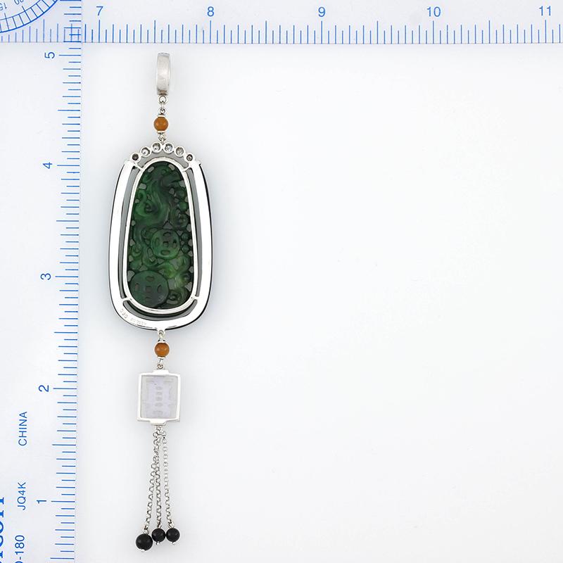 What an amazing, one-of-a-kind, designer jade & 18K white gold pendant. A natural dark green jade carving is the centerpiece of this design. The carving is approx. 17 x 36.5 x 2mm and depicts a carved dragon with two coins. The dragon is a symbol of