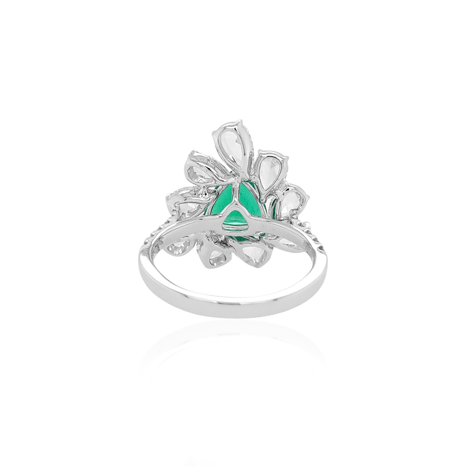 A bold statement K18 White Gold cocktail ring features a superb quality Trilliant shape Colombian Emerald at its centre, set amongst an elegant arrangement of Pear Shape Rose Cut White Diamonds halo. Unique and striking, this exceptional ring will