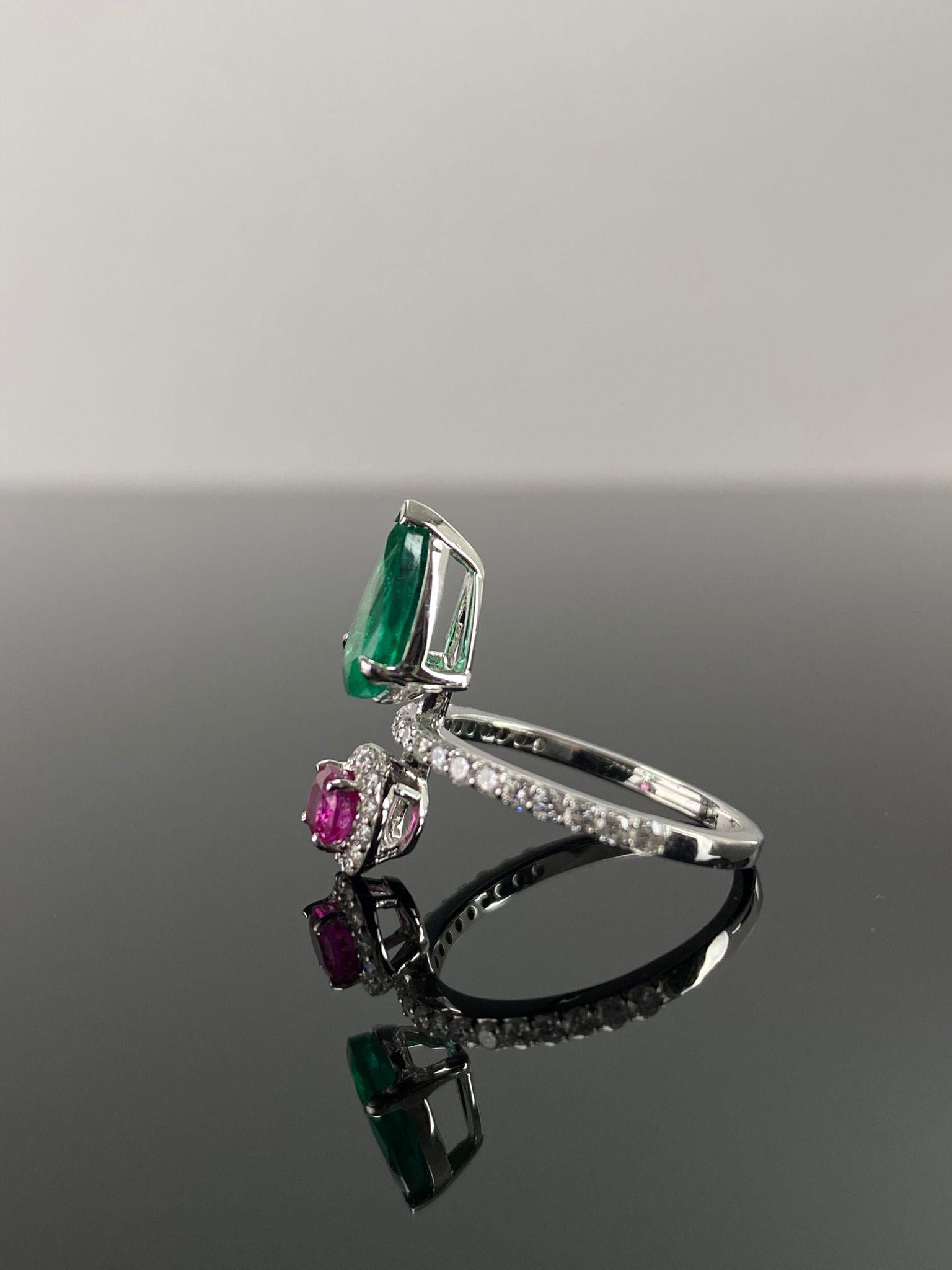 Dieser einzigartige Ring aus 18 Karat Weißgold ist mit einem 0,51 Karat schweren Diamanten im Rundschliff und einem 0,58 Karat schweren Rubin im Ovalschliff auf der einen Seite und einem natürlichen birnenförmigen Smaragd aus Sambia von 1,57 Karat