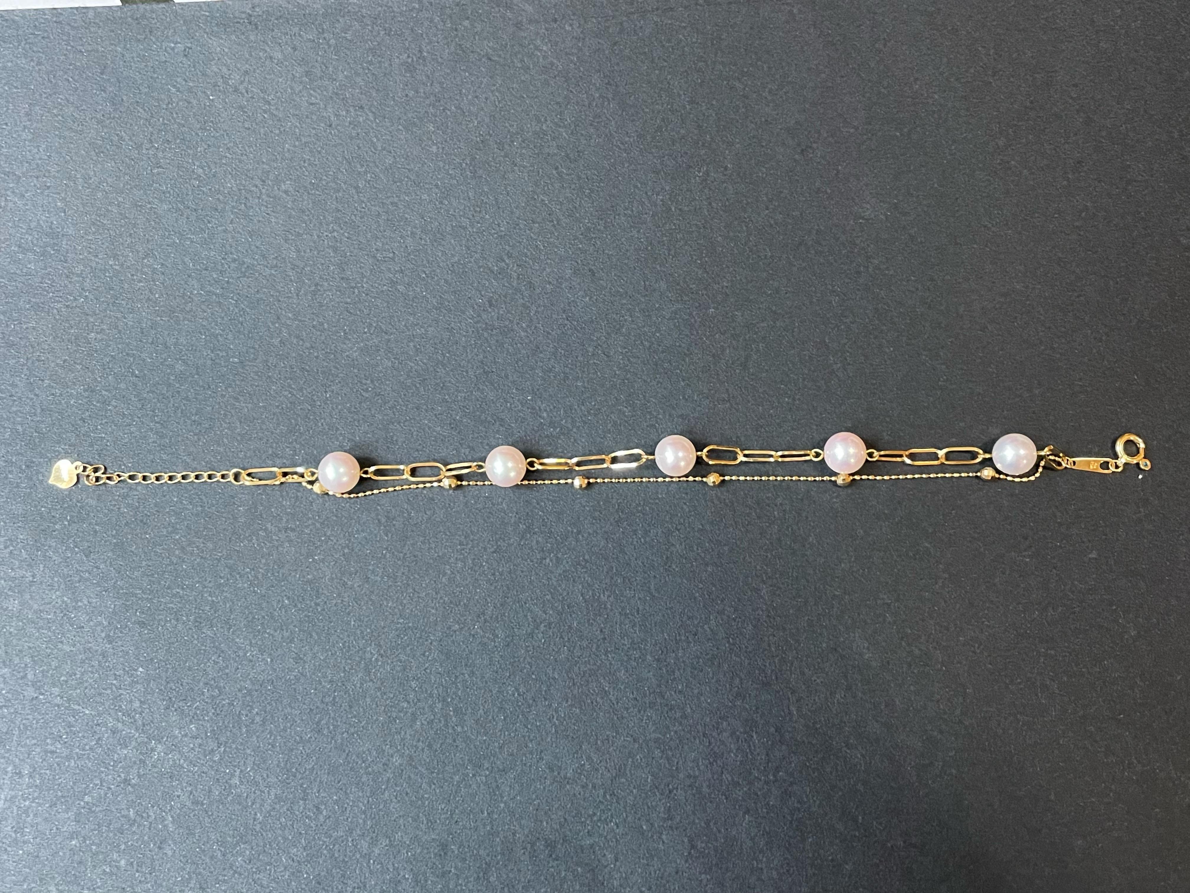 Experience the perfect blend of simplicity and modern elegance with our exquisite double-layer gold chain bracelet. This stunning piece showcases five natural Japanese Akoya pearls, each thoughtfully arranged to create a harmonious balance of beauty