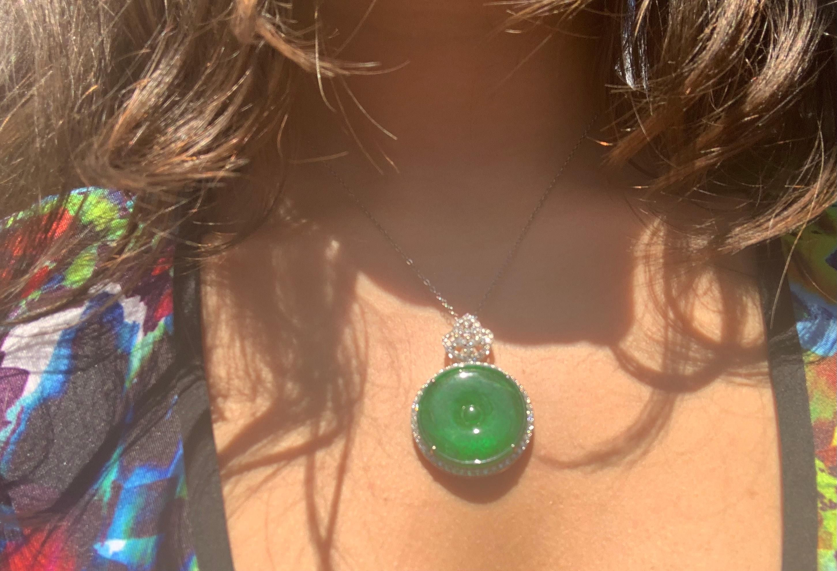 Estate sourced fine natural green jade disc pendant mounted in 18k white gold diamond encrusted setting. The back engraved with a scrolled foliate motif by a master goldsmith. 75 round and 3 marquise-shaped diamonds totaling approximately 1.25