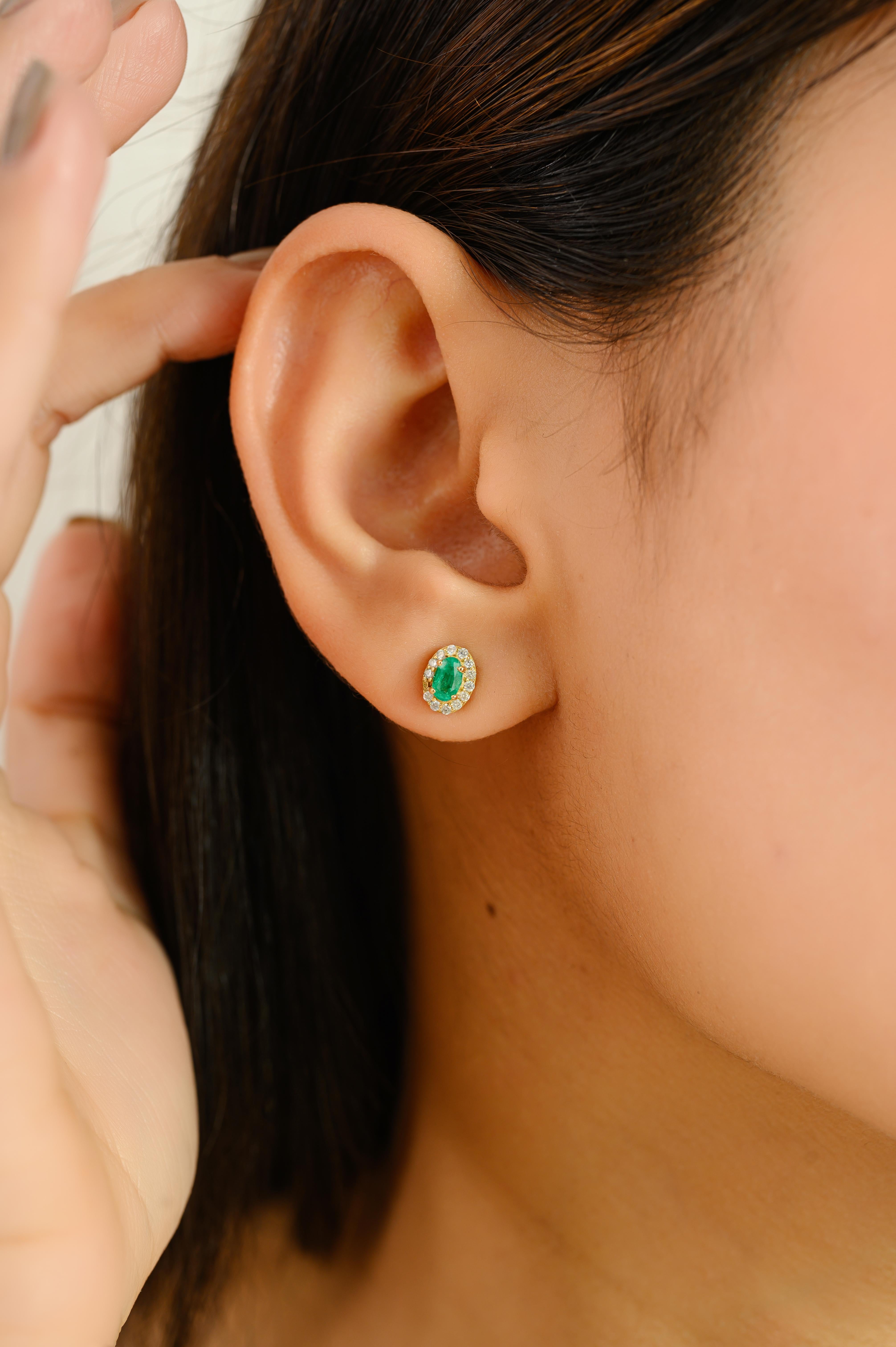 Elevate your jewelry collection with these exquisite stud earrings, crafted in 18k yellow gold. Each earring showcases a vibrant oval-cut emerald with a total gemstone weight of 0.45 carats, beautifully framed by a halo of dazzling round-cut